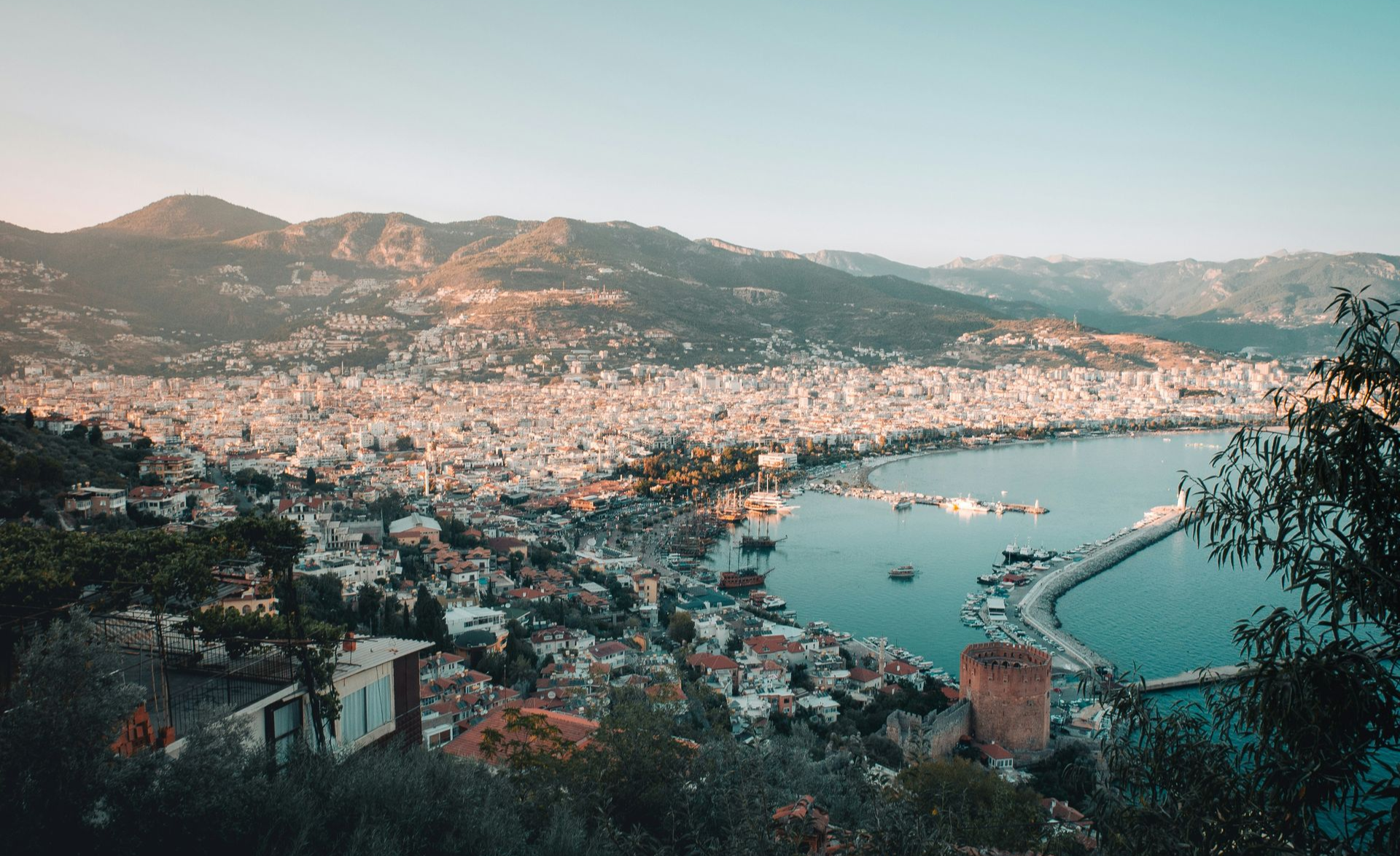 Coastal city with a harbor, surrounded by mountains. Buildings sprawl along the coast in Turkey.