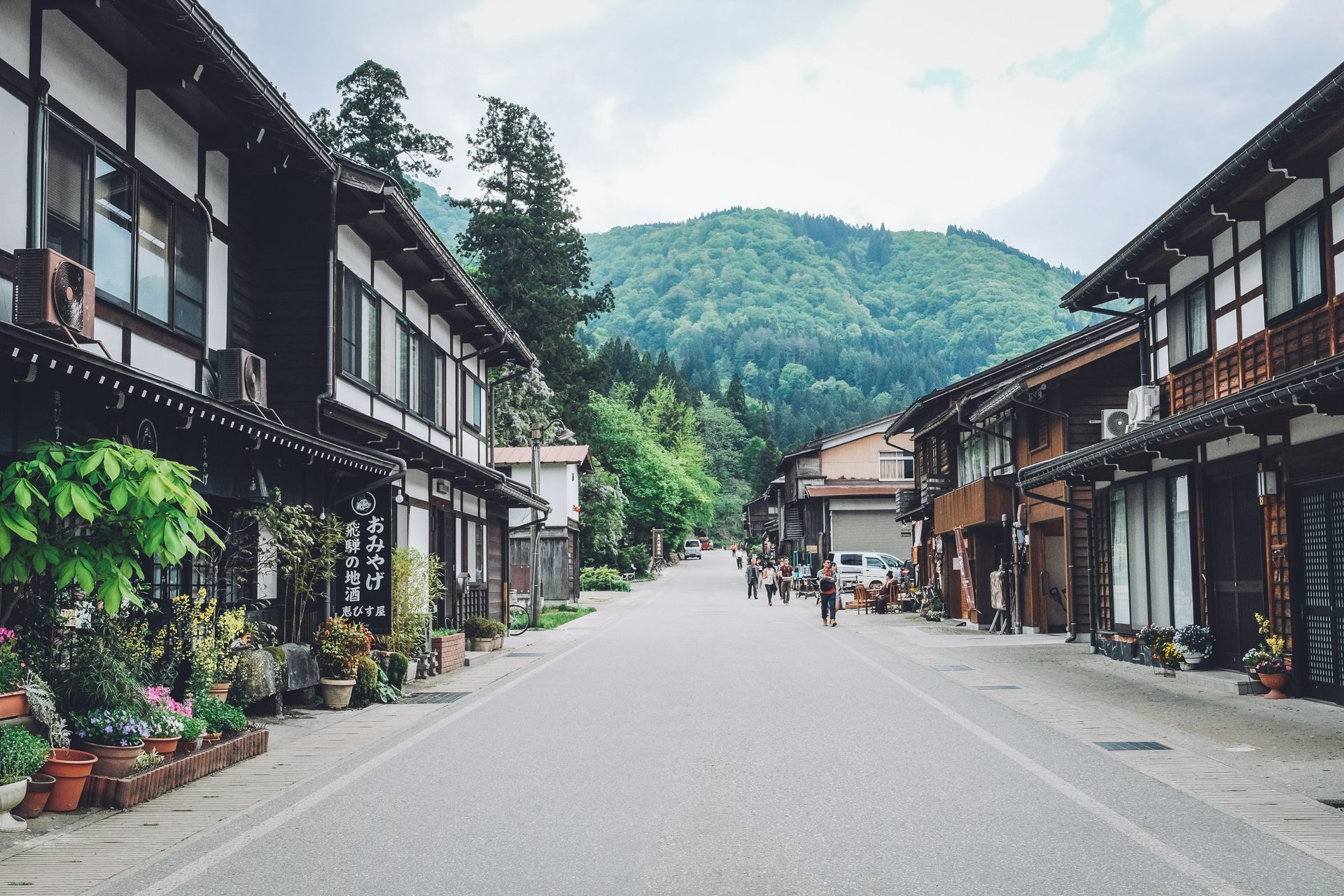 A road lined with traditional Japanese buildings, with a mountain in the background, in Shirakawa, Japan. 