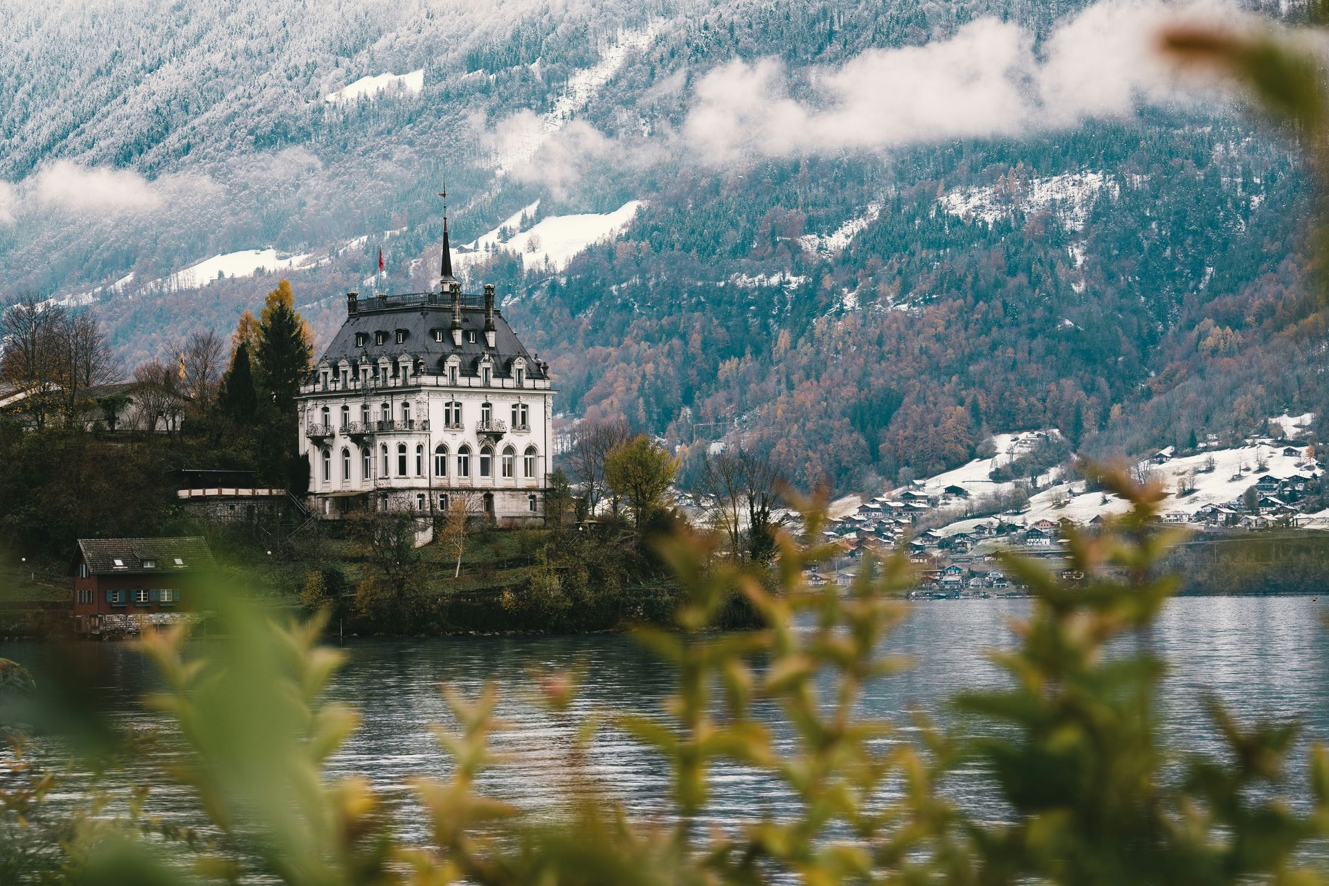 The elegant Seeburg Castle on Lake Brienz, snow-covered mountains in the background in Iseltwald, Switzerland.