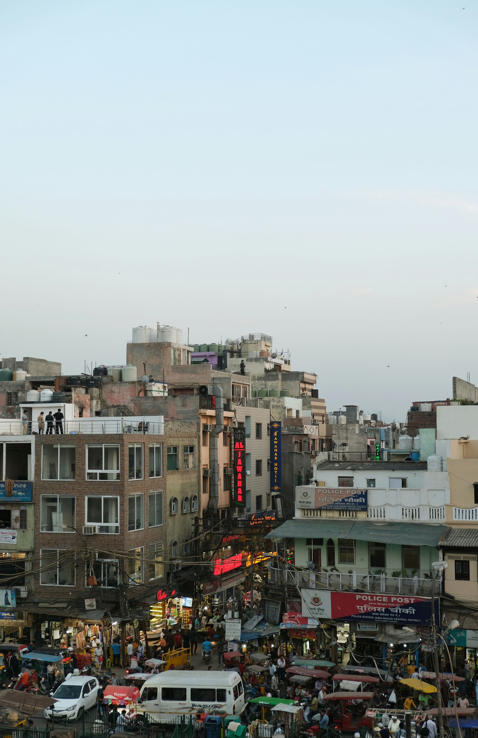 Busy cityscape with crowded street and buildings at dusk in New Delhi, India.