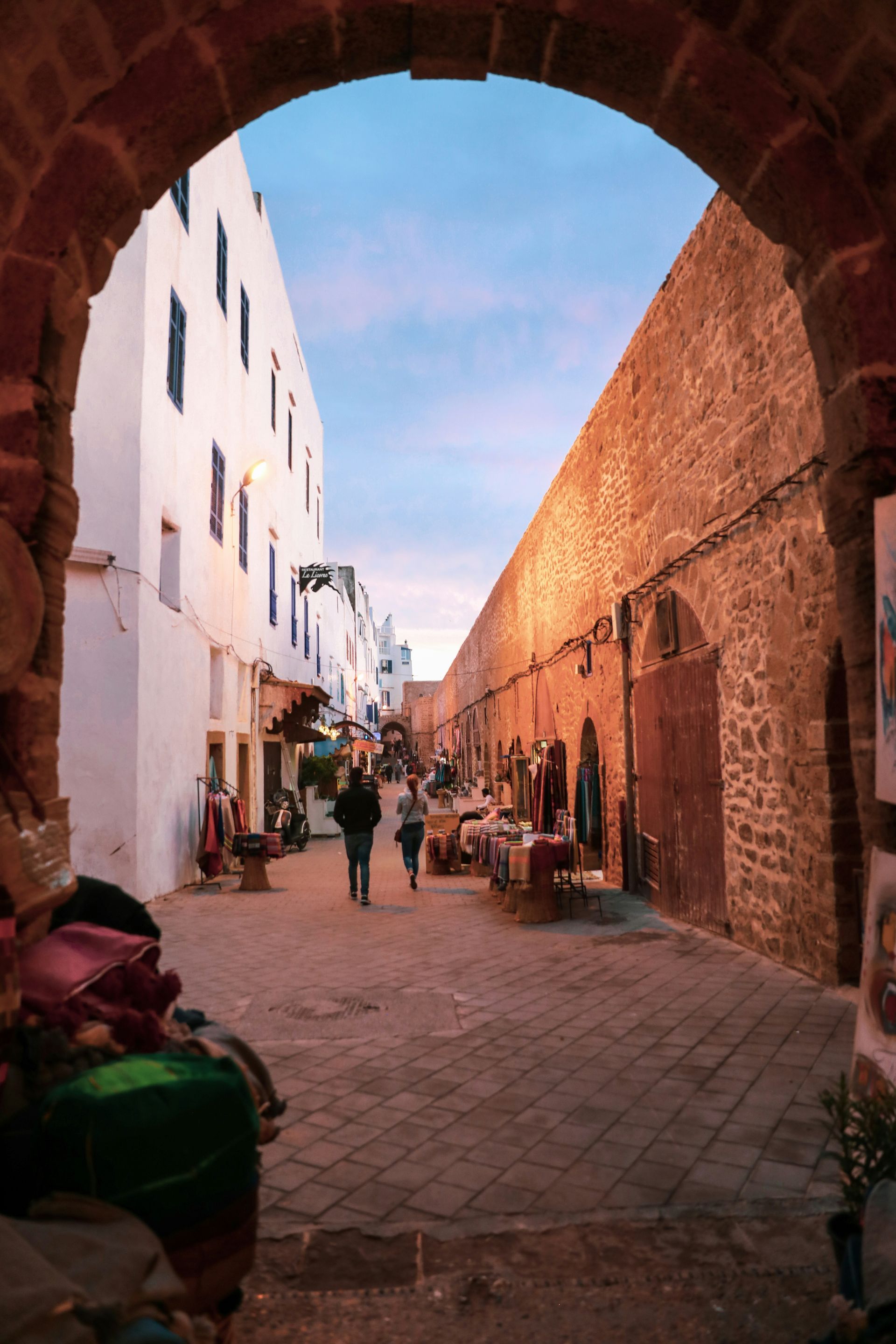 A group of people are walking down a narrow street in Essaouira, Morocco.