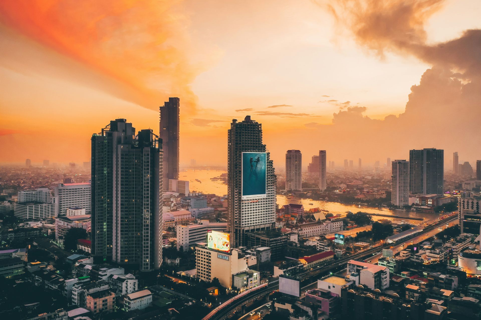 An aerial view of Bangkok, Thailand at sunset with a river in the foreground.