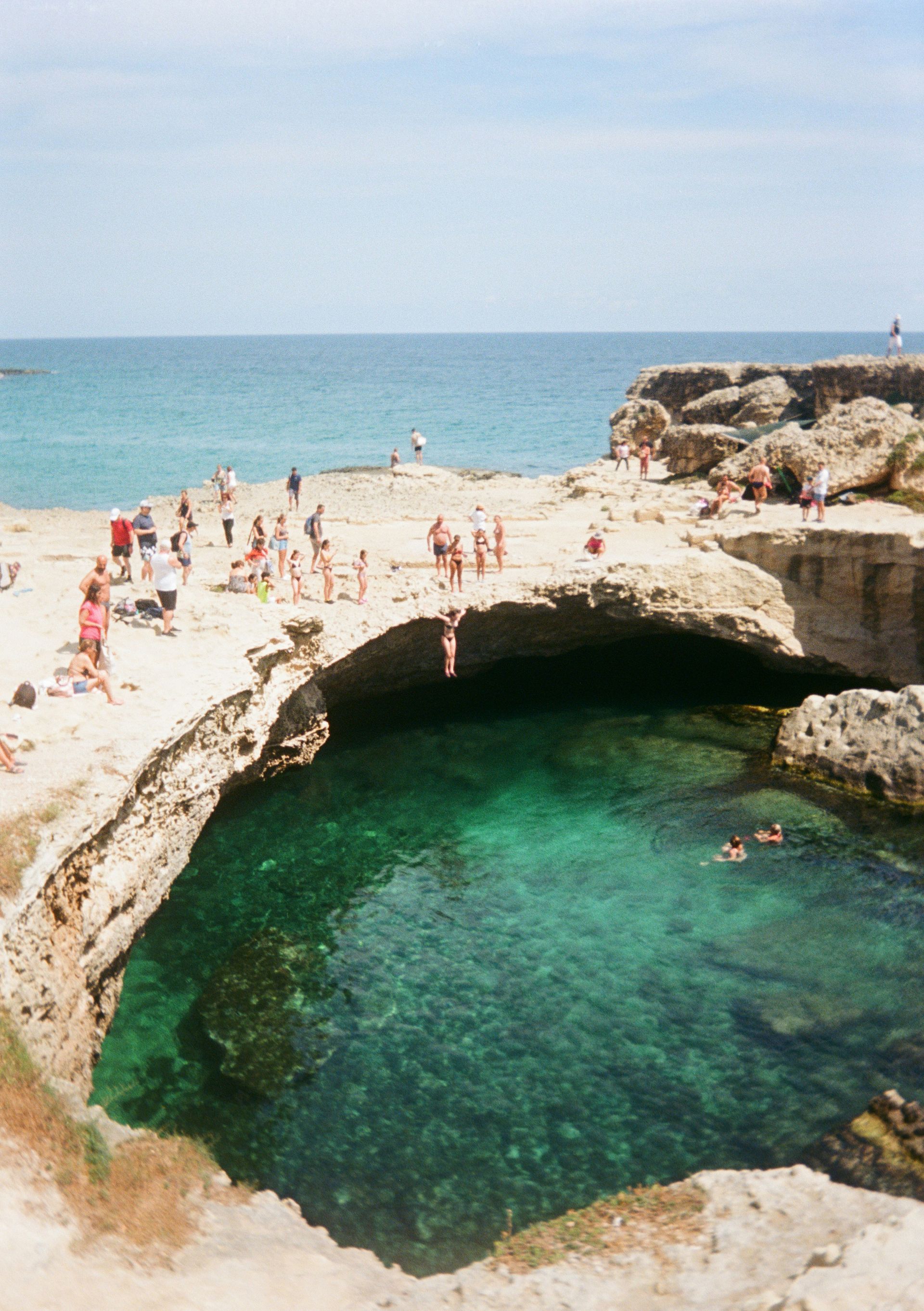 A group of people are swimming in a pool on a beach in Puglia, Italy.