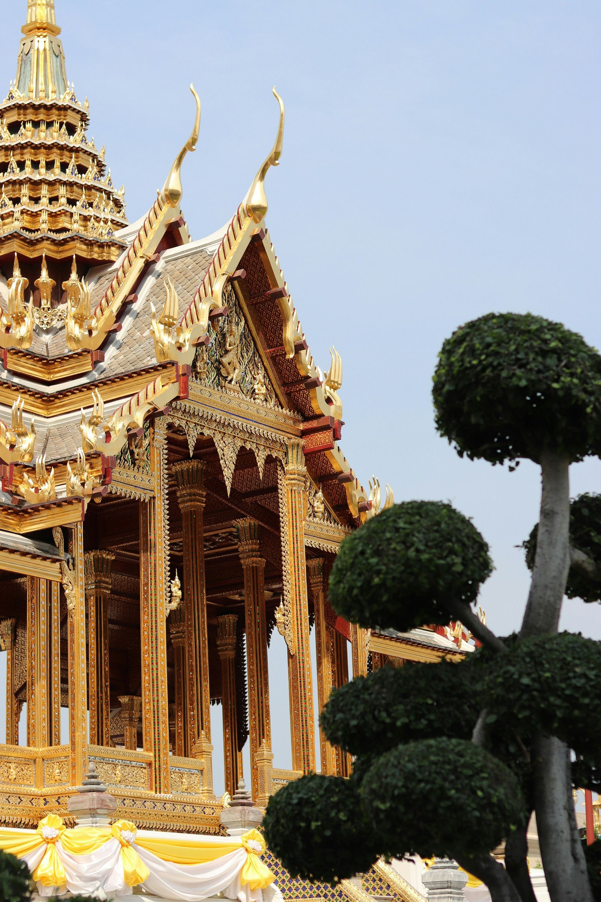 A very ornate building with trees in front of it in Bangkok, Thailand.