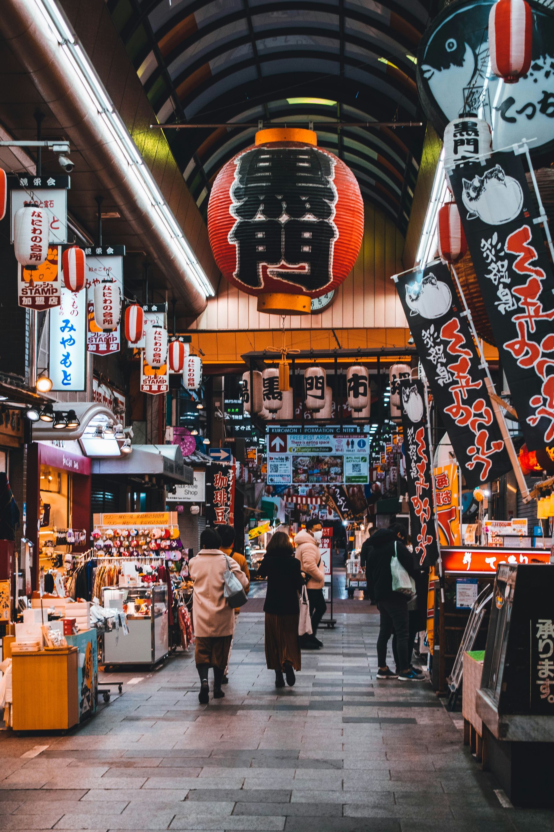 Bustling Japanese market alleyway, lined with stalls and colorful lanterns in Osaka, Japan.