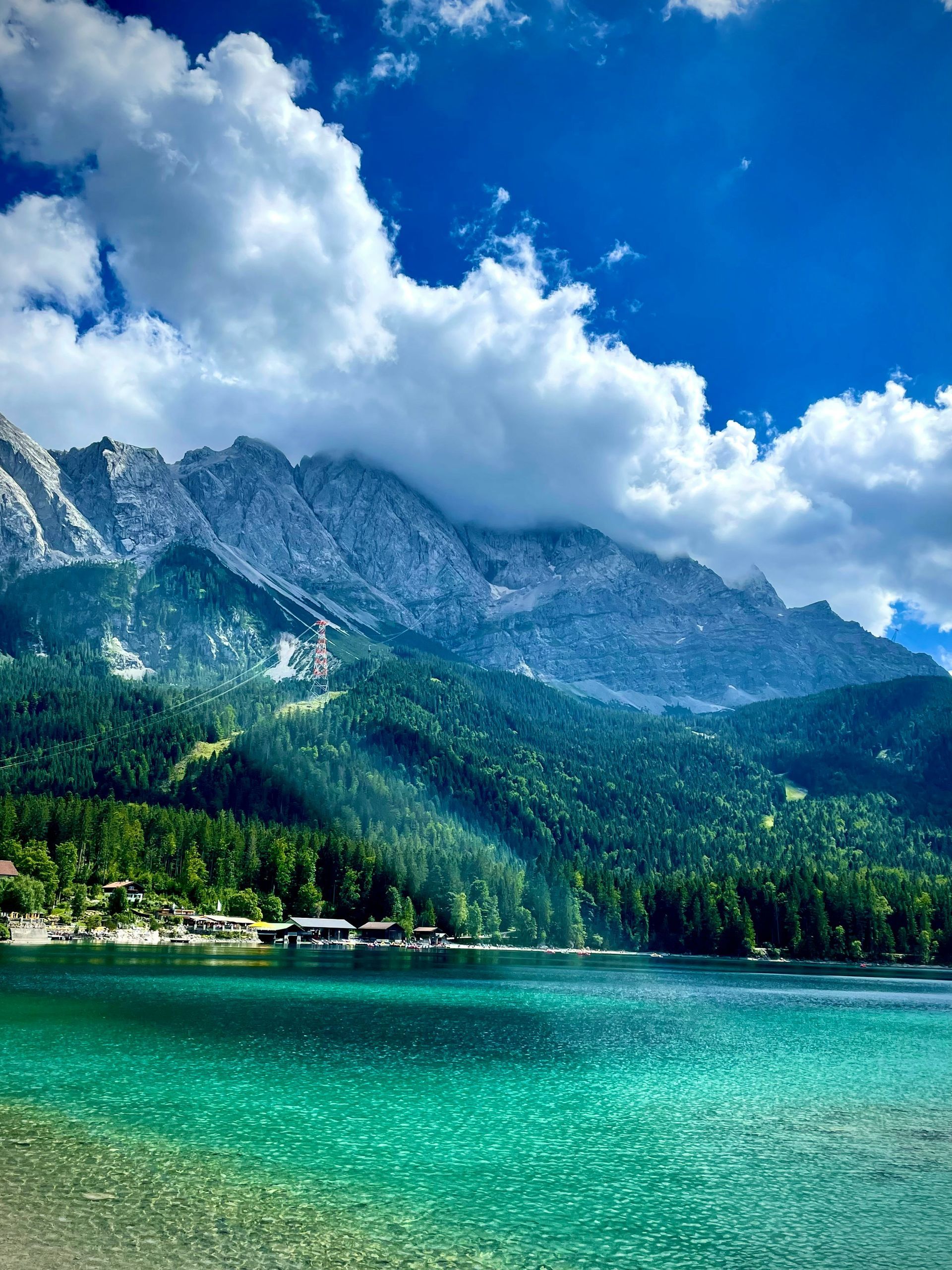 Emerald lake beneath a mountain, vibrant blue sky in the Bavarian Alps of Germany.