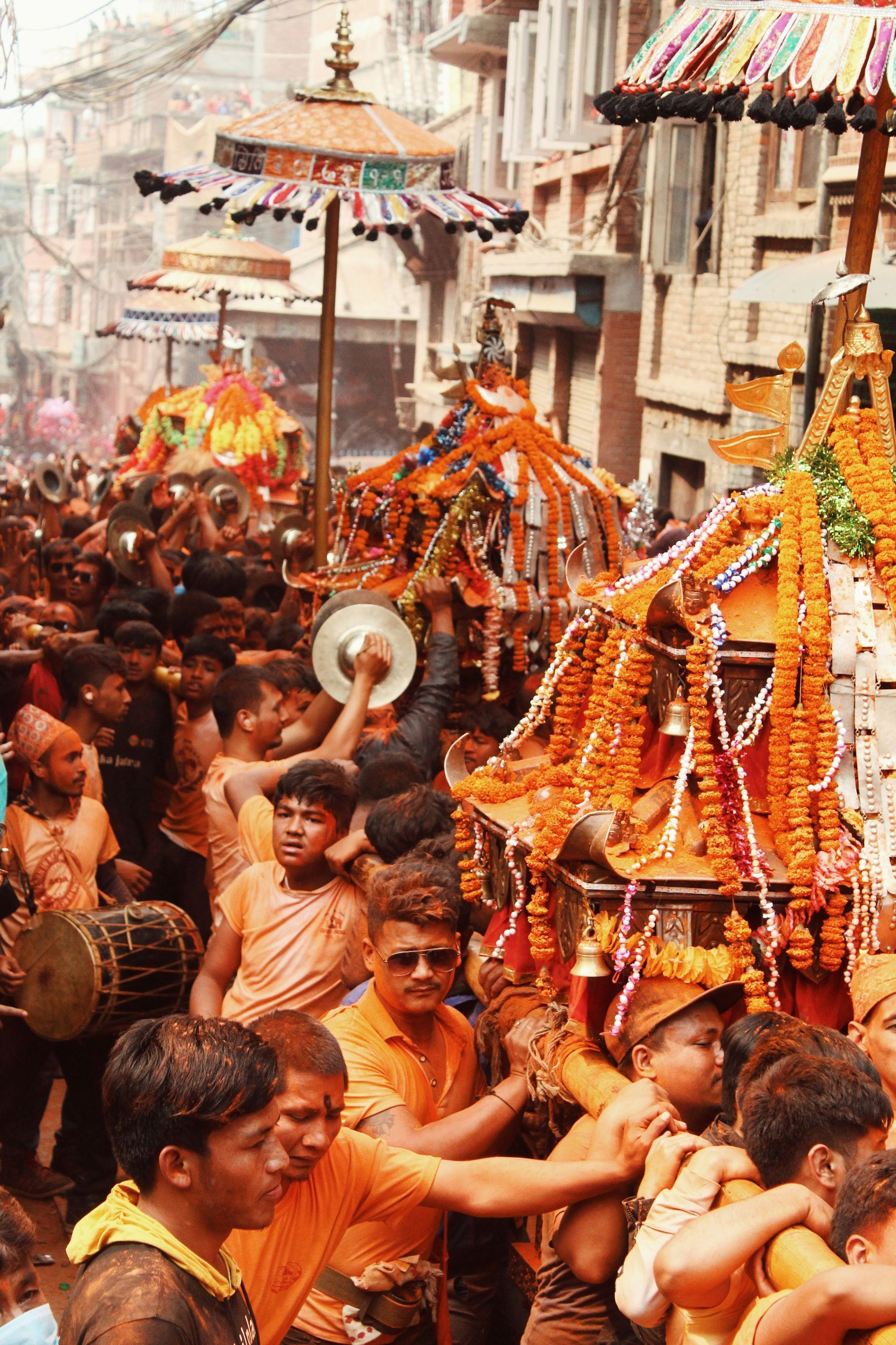 People carrying ornate floats through a crowded street during a festival in Bhaktapur, Nepal.