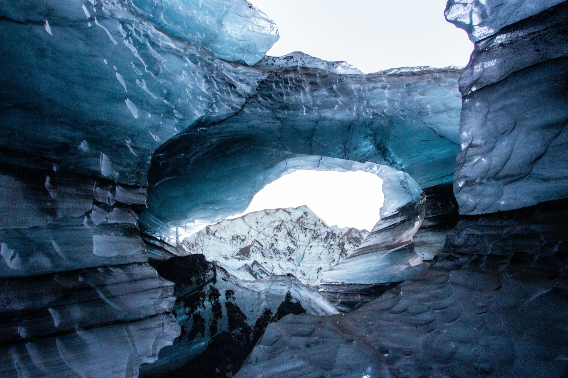 Inside a glacier cave, viewing a mountain peak through an opening in the Blue Ice Caves, Iceland.