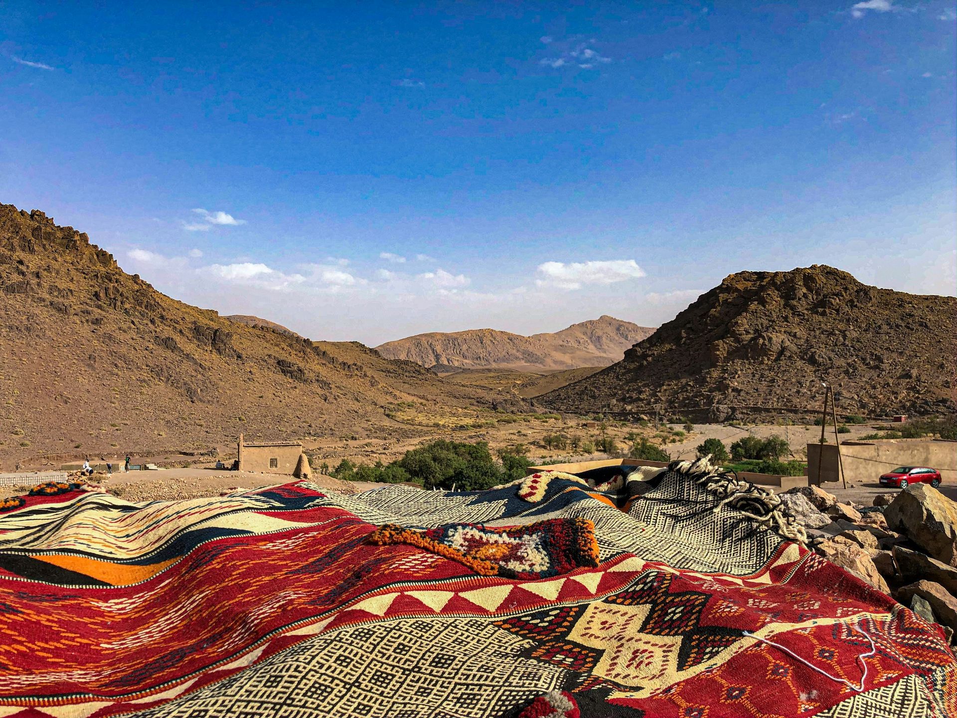 Rugs are lying on top of each other in the desert with mountains in the background in Ouarzazate, Morocco.