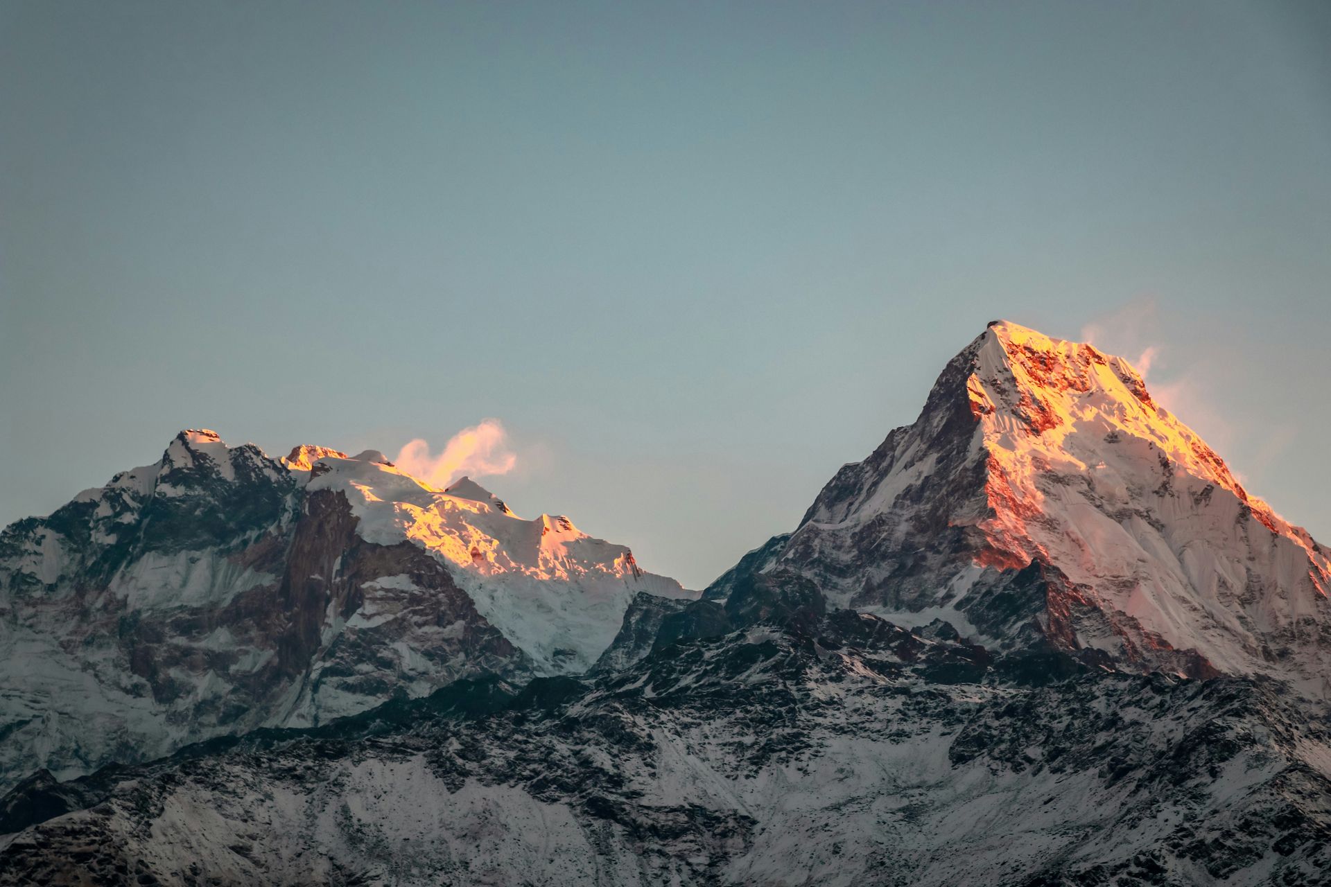 Snow-capped mountains peak, bathed in warm sunlight in Annapurna, Nepal.