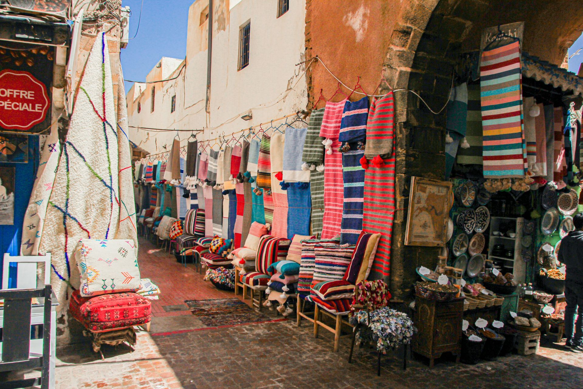 A narrow street with a market selling fabric in Essaouira, Morocco.