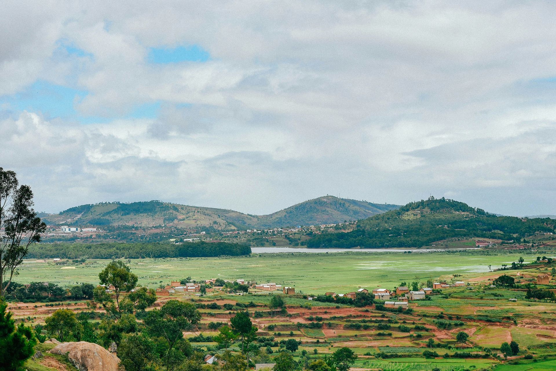 Rolling green hills and fields with a lake in Ambositra, Madagascar.
