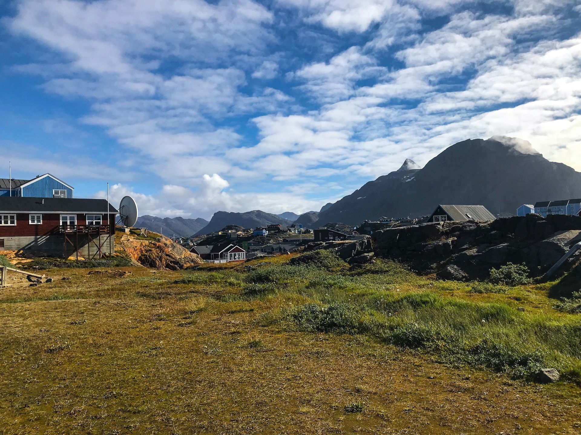 Colorful houses, rocky hills, and cloudy blue sky in Sisimiut, Greenland.