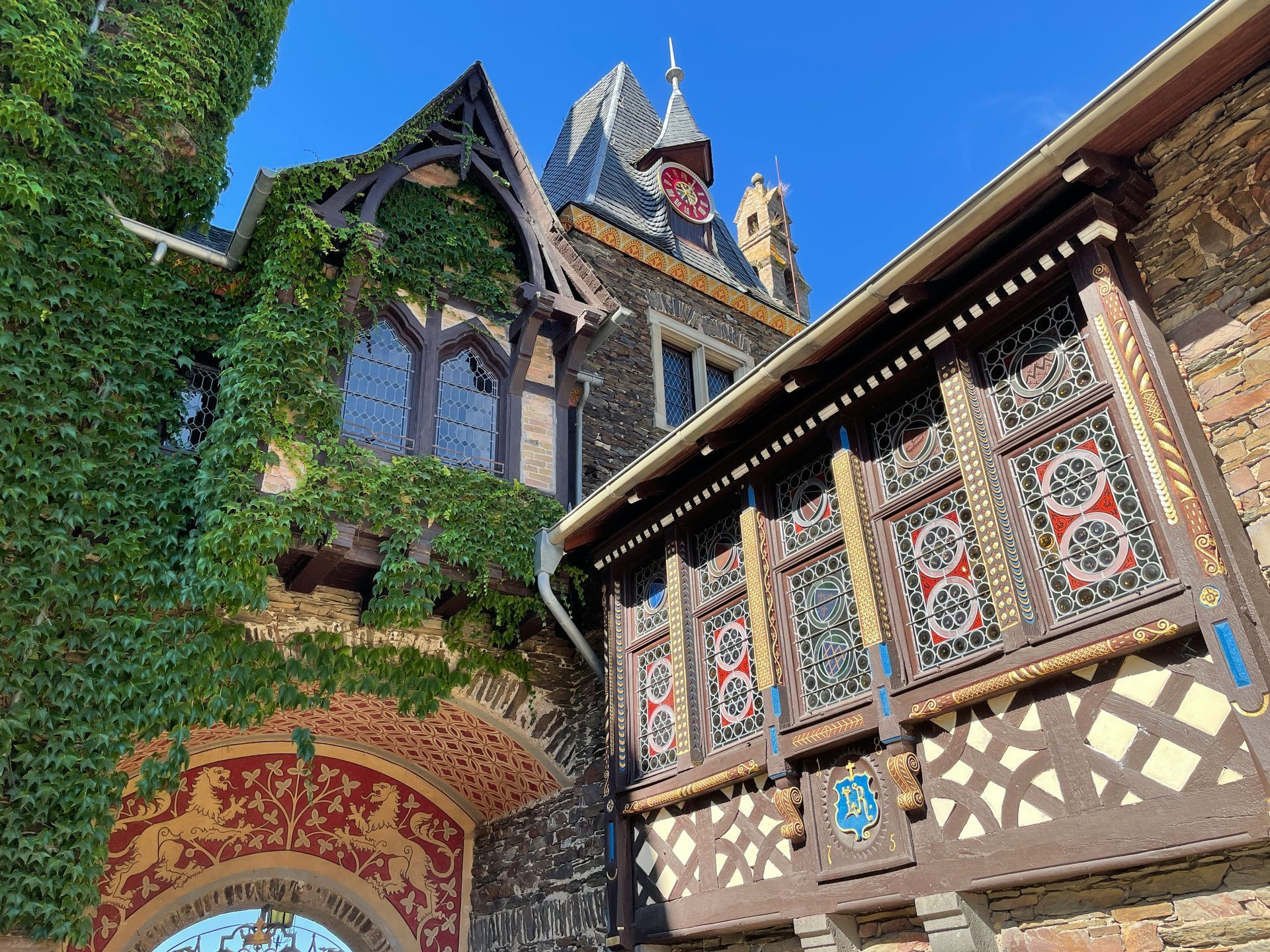 Gothic castle entrance with ivy-covered walls, ornate woodwork, stained glass windows in Cochem, Germany.