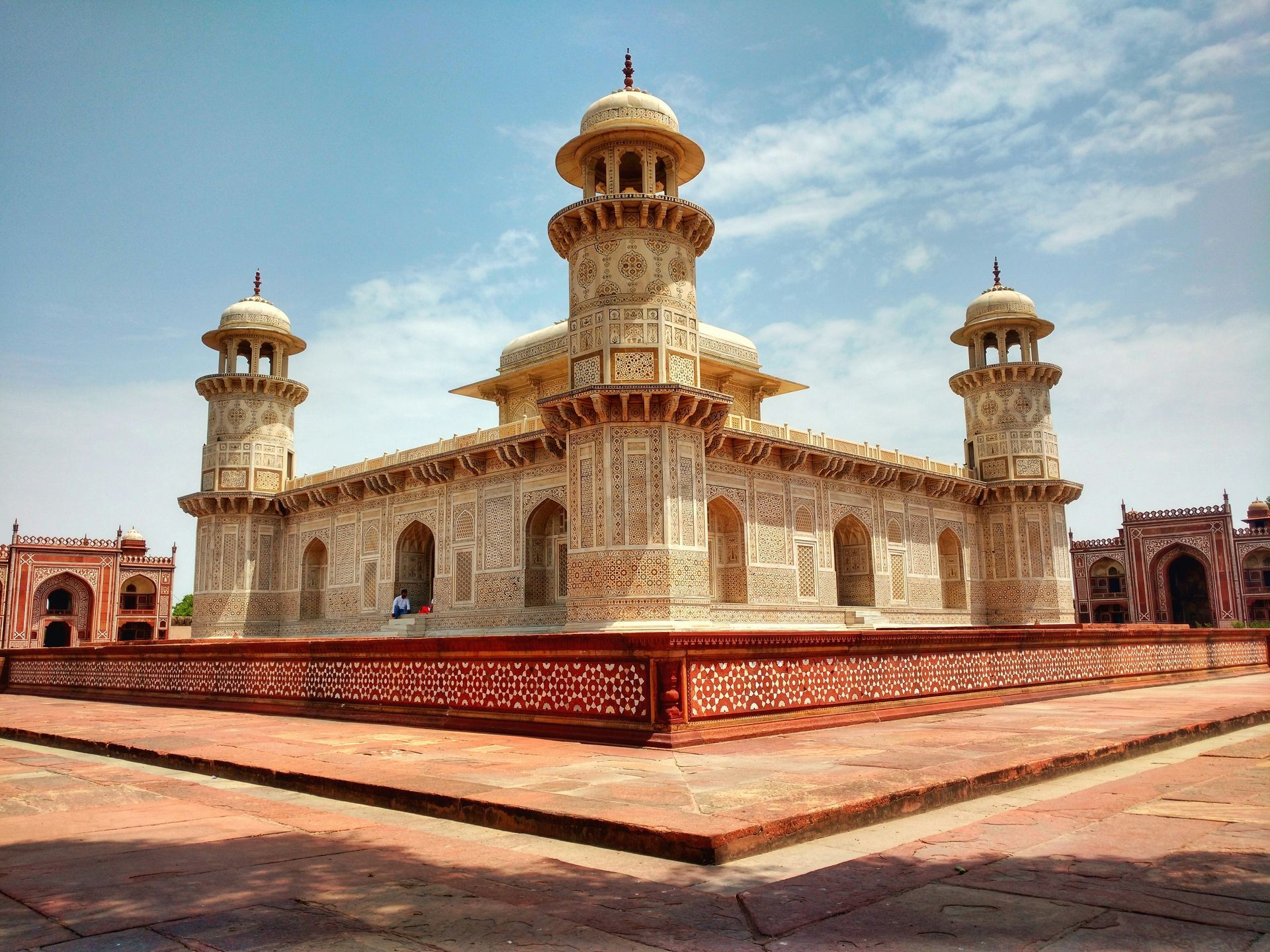 White marble Tomb of I'timād-ud-Daulah, Agra, India, with ornate details, against a blue sky.