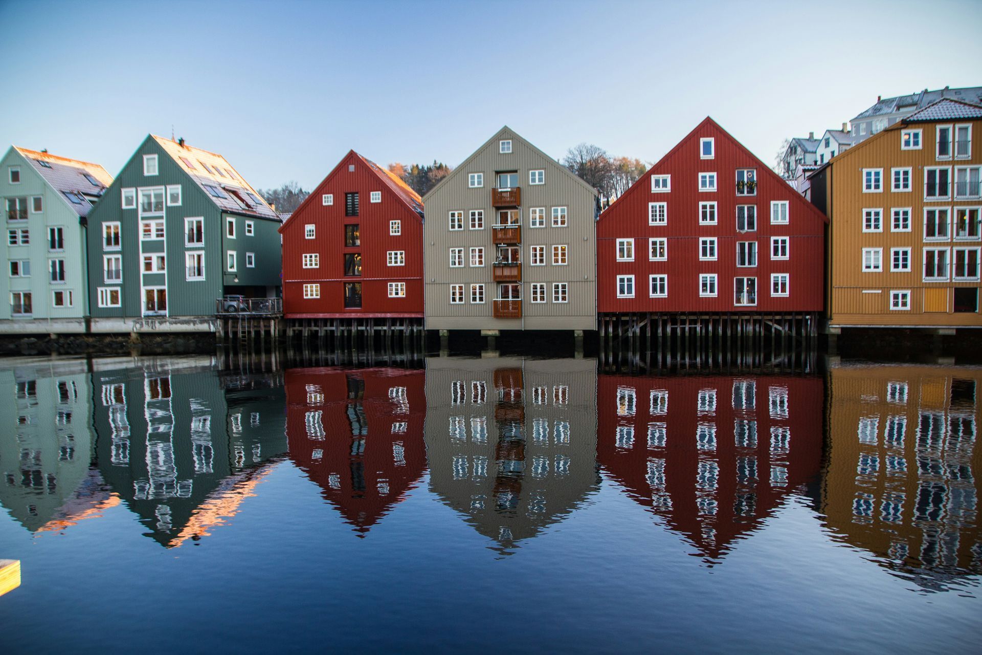 Colorful waterfront buildings reflected in the calm water of Trondheim, Norway.