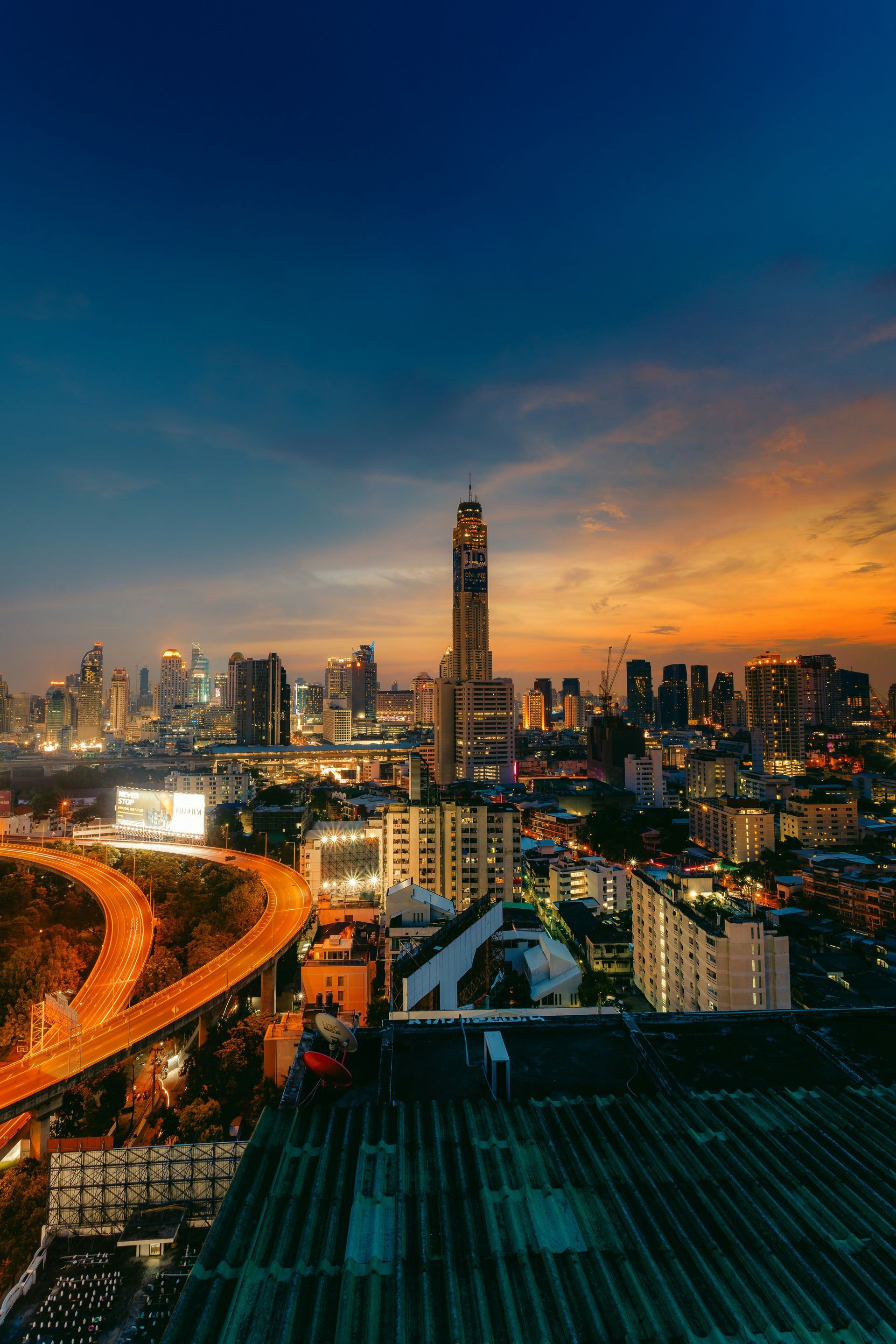 An aerial view of Bangkok at night with a clock tower in the foreground.