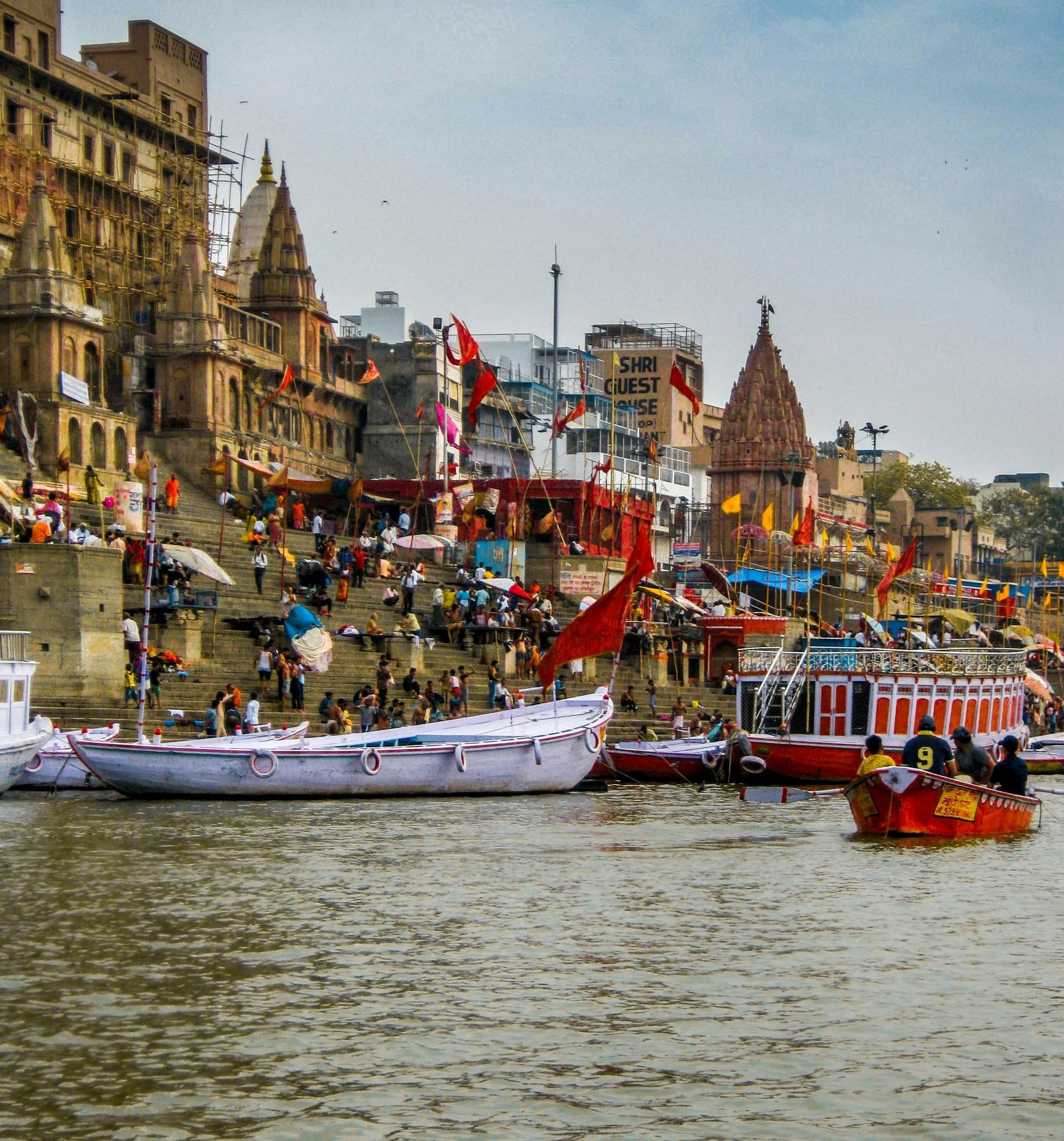 A man is sitting in a boat on a river in front of Varanasi, India.