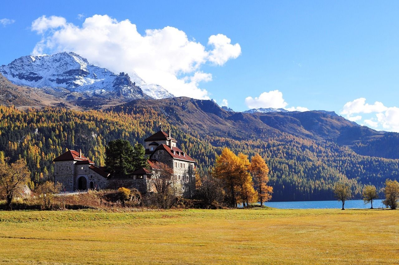 A castle in the middle of a field with mountains in the background in Switzerland.