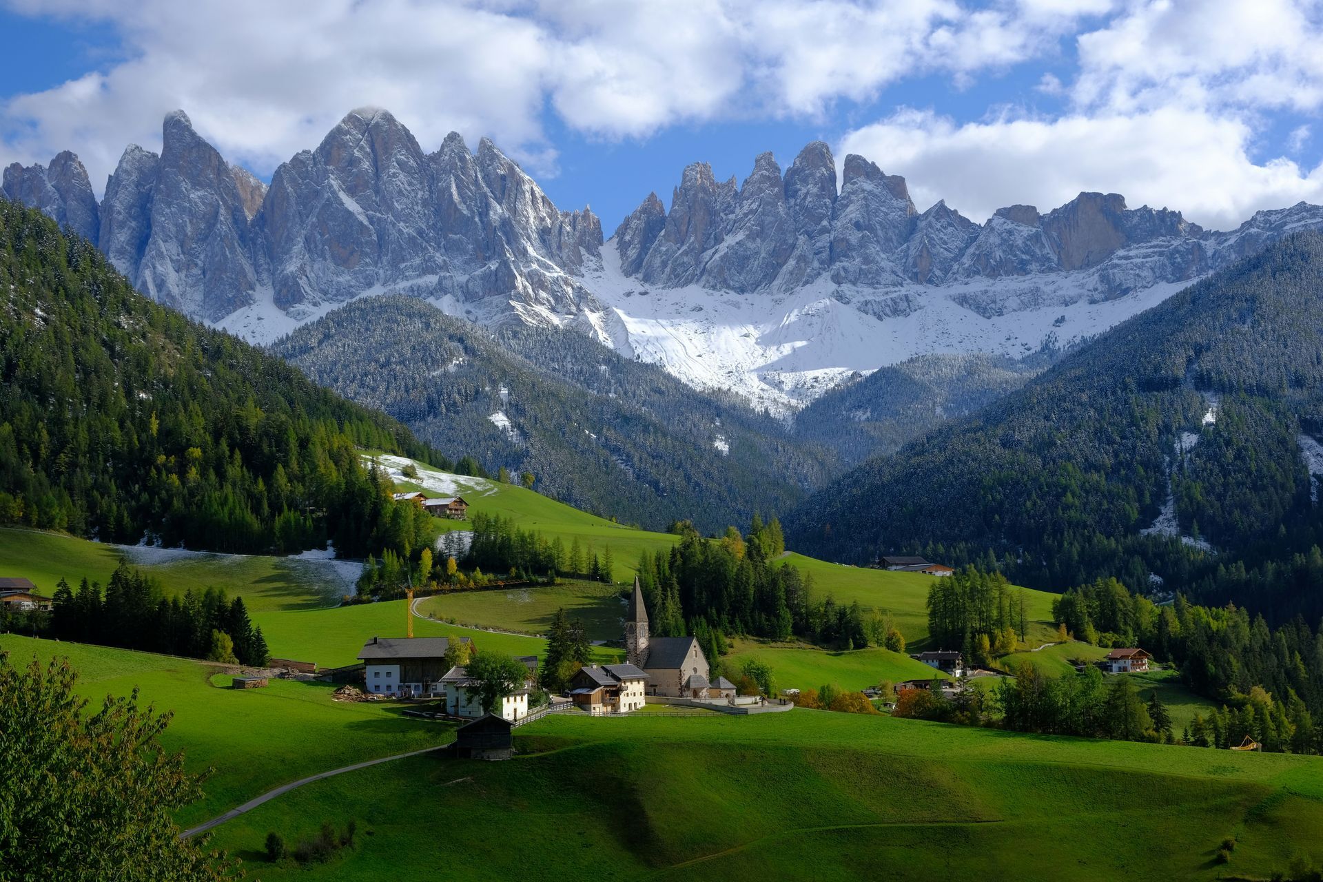 A valley with the Dolomites in the background and a church in the foreground in Italy.