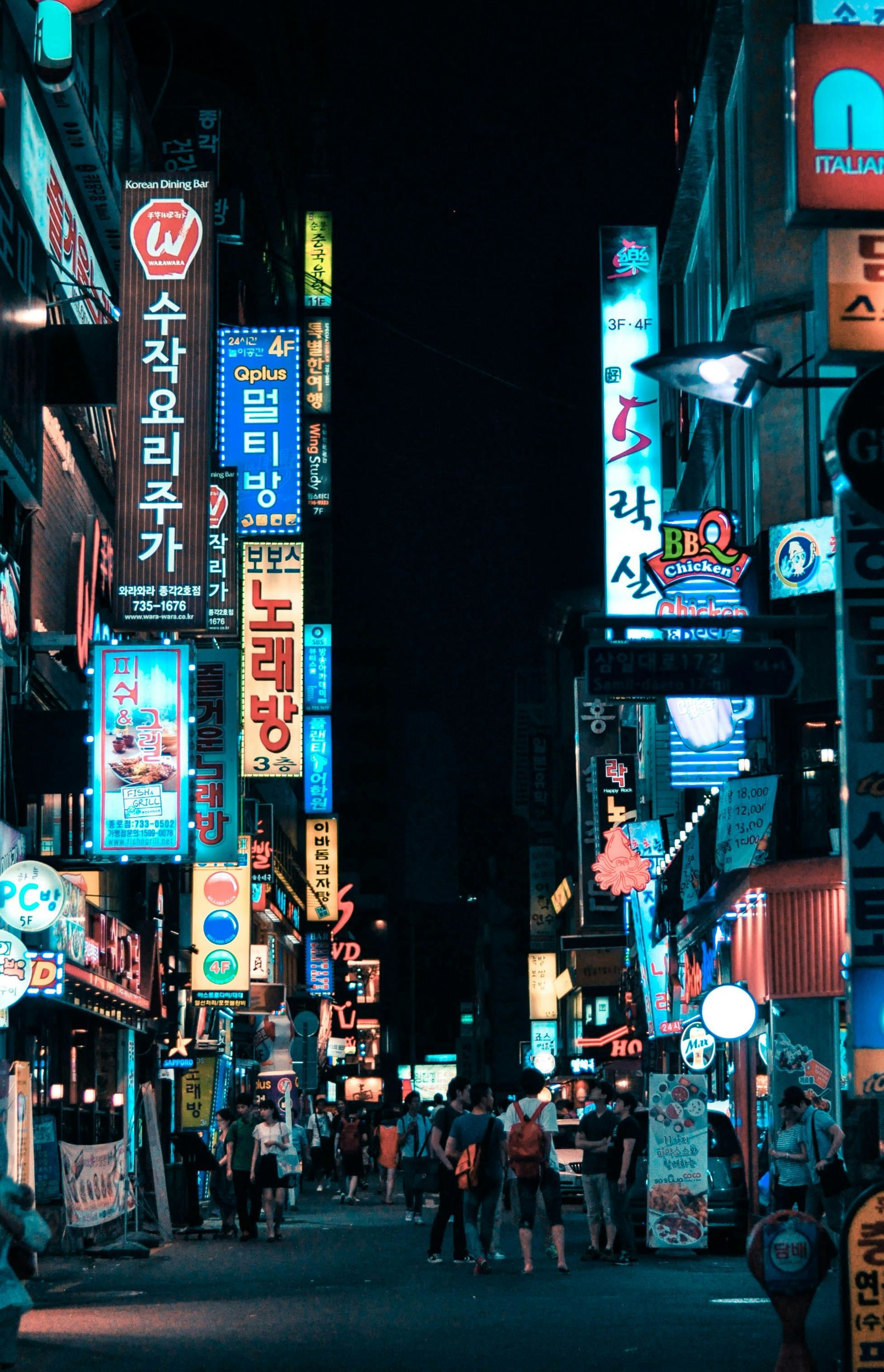 Neon-lit street in Seoul at night. Signs in various colors, people walking on the road in South Korea.