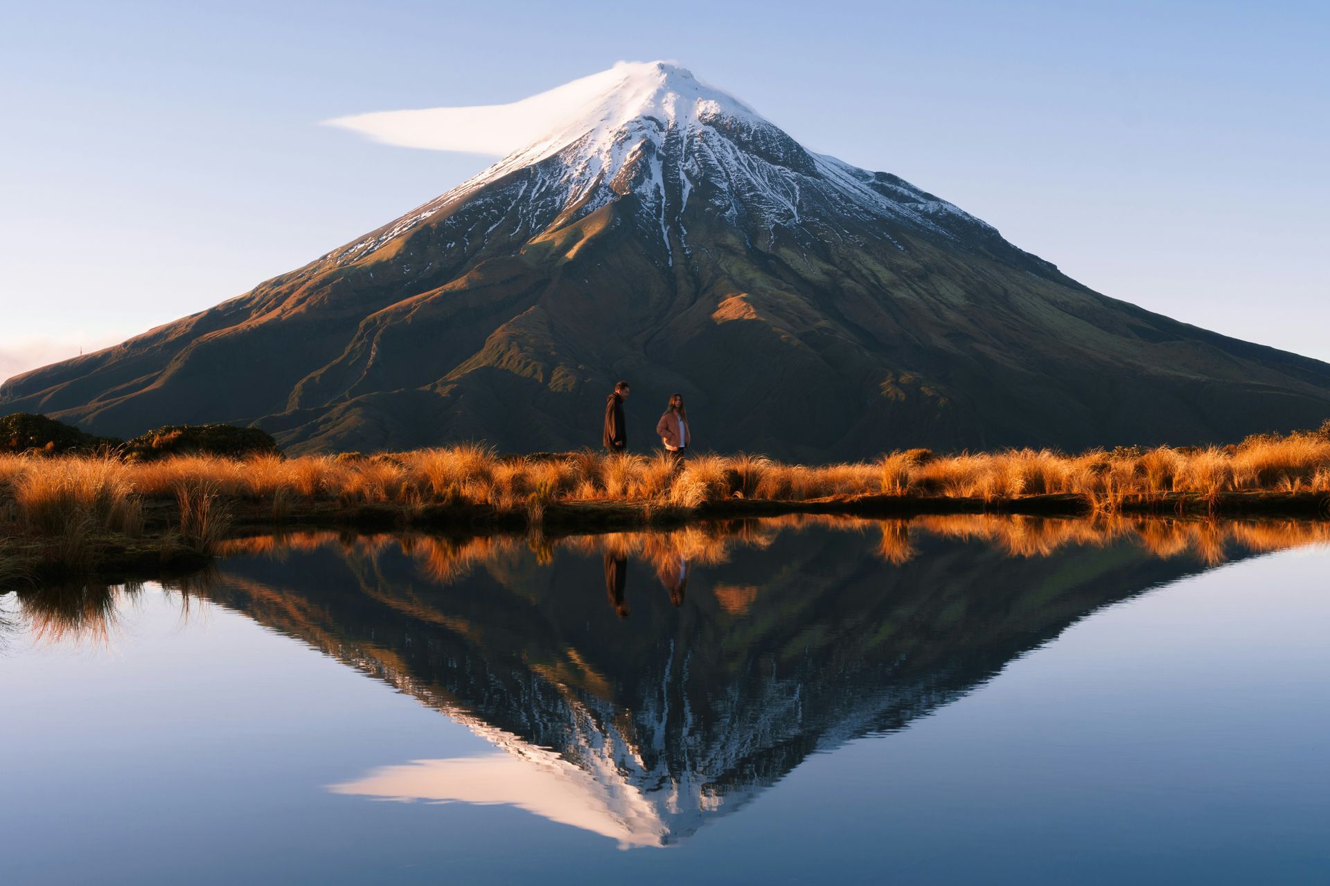 Mount Taranaki is reflected in the water of Lake Mangamahoe in New Zealand.