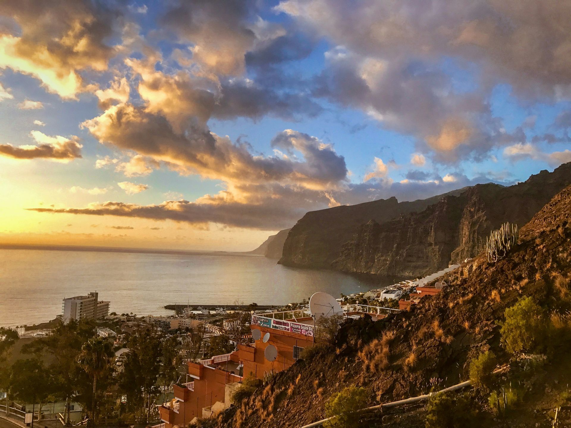 Coastal sunset over town and mountains. Orange, blue, and white clouds on the Canary Islands, Spain.