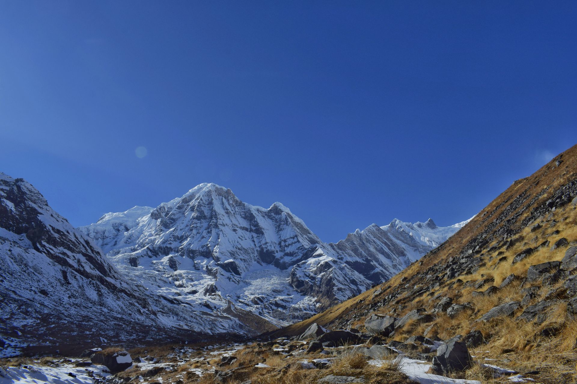Snow-capped mountains; a valley with sparse vegetation in Annapurna, Nepal.