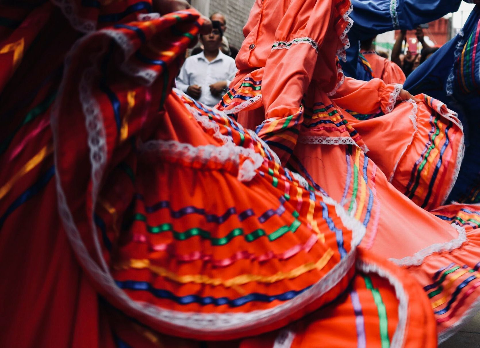 Close-up of dancers in bright red dresses with colorful ribbons in Mexico.