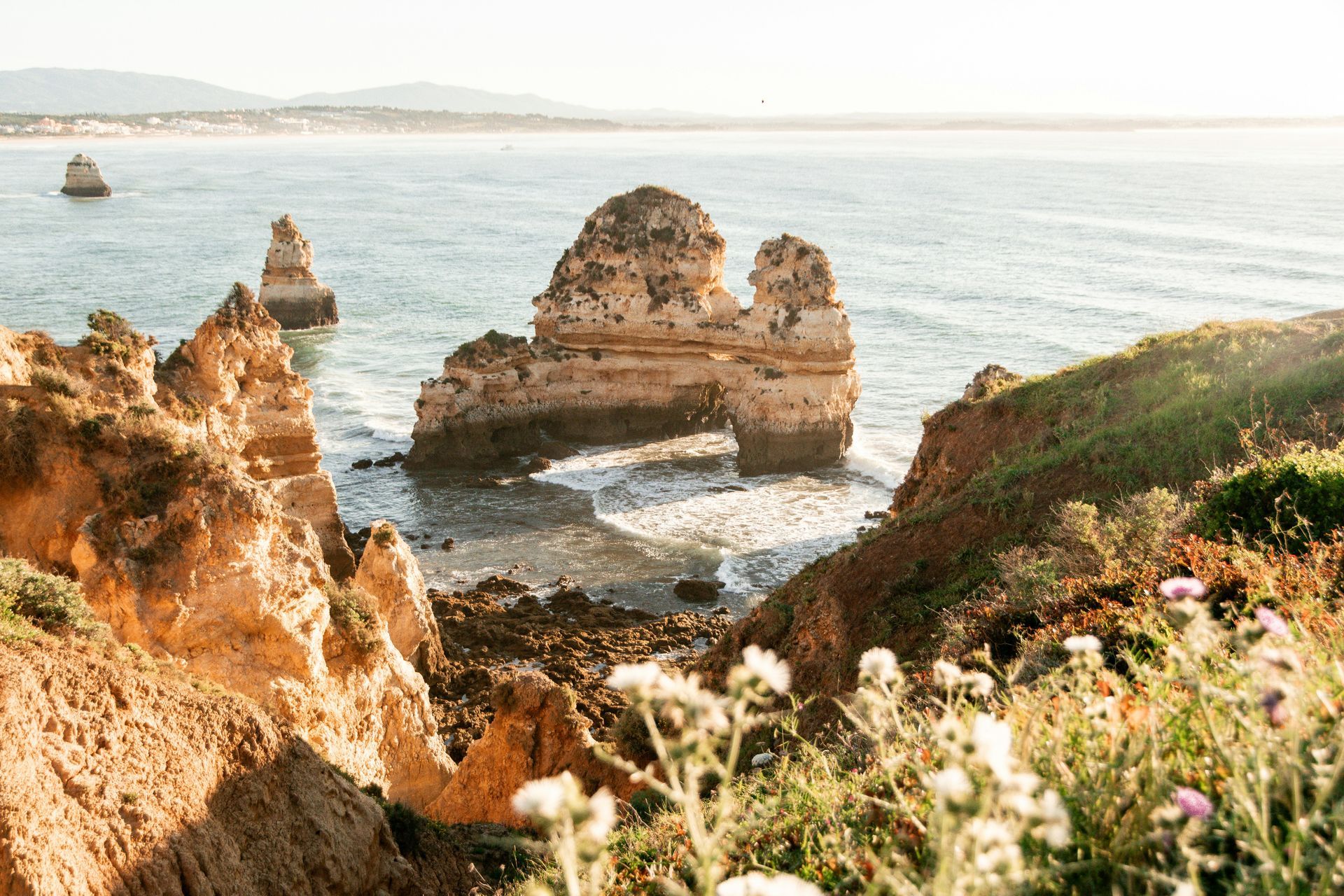 Coastal cliffs with rock formations in the ocean; sunny day in the Algarve, Portugal.