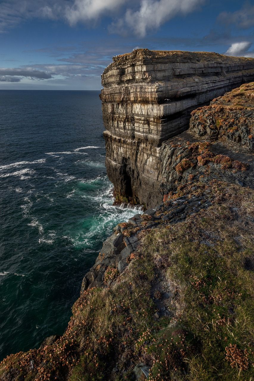 The Cliffs of Moher overlooking the ocean with waves crashing on the rocks in Ireland.