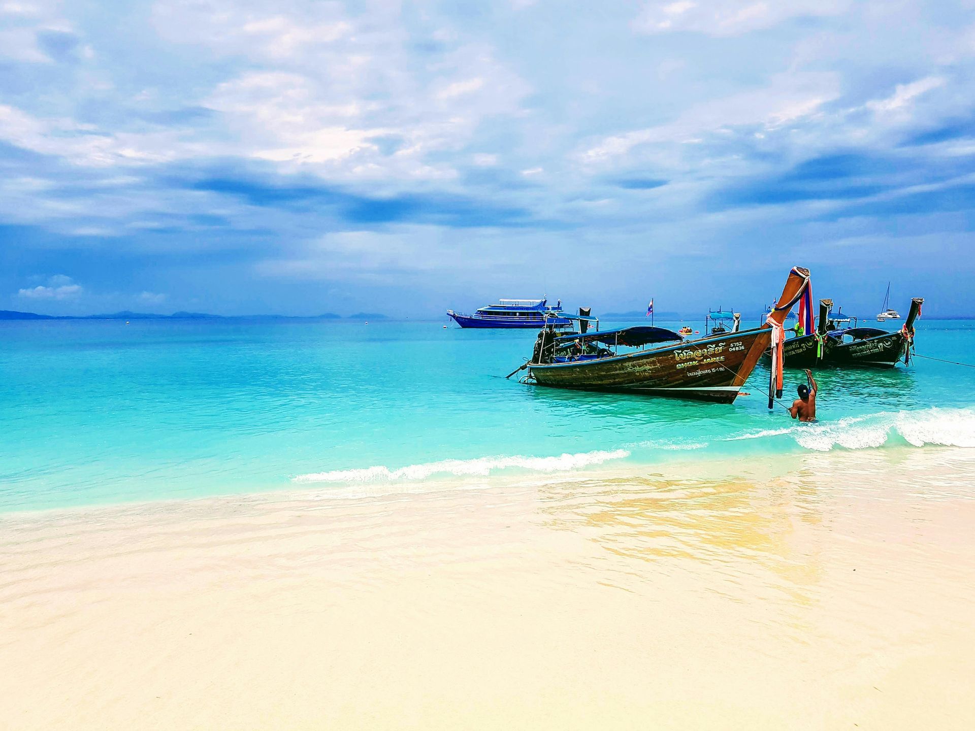 A couple of boats are sitting on top of a sandy beach in Phuket, Thailand.