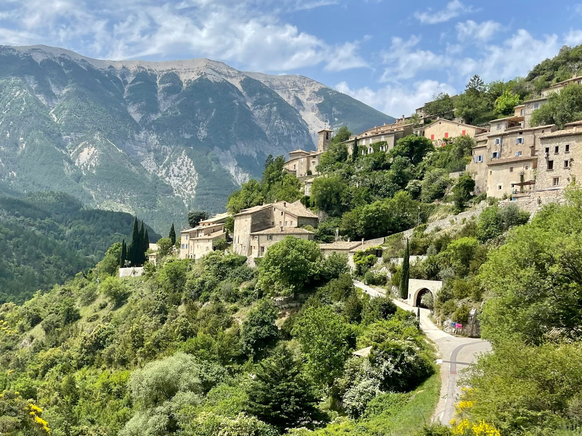 A small village on a hillside with mountains in the background in Provence, France.