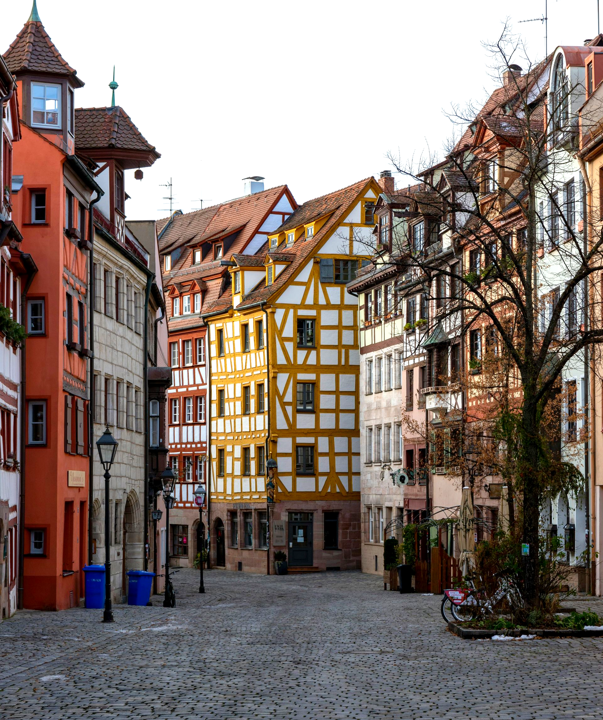 Cobblestone street in Nuremberg, Germany, lined with colorful half-timbered  medieval buildings.