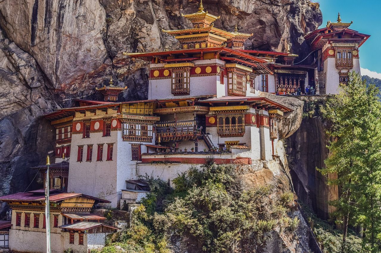 Tiger's Nest Monastery, Bhutan, clings to a cliff. White, red, and gold Buddhist temple with elaborate architecture.