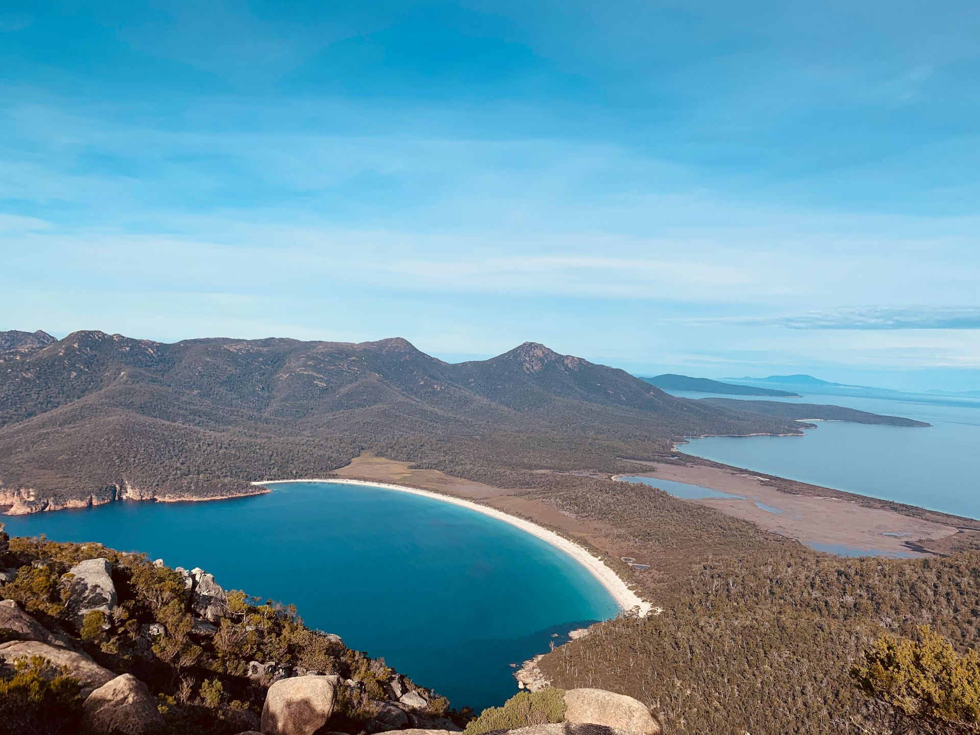 A large body of water surrounded by mountains and trees in Tasmania, Australia.