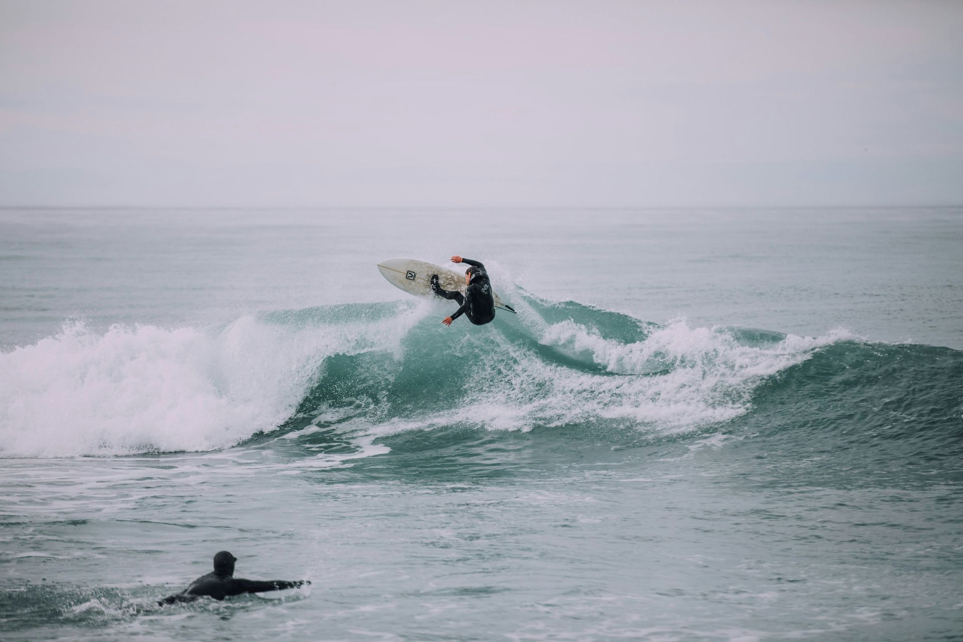 A man is riding a wave on a surfboard in the ocean in Kaikōura, New Zealand.