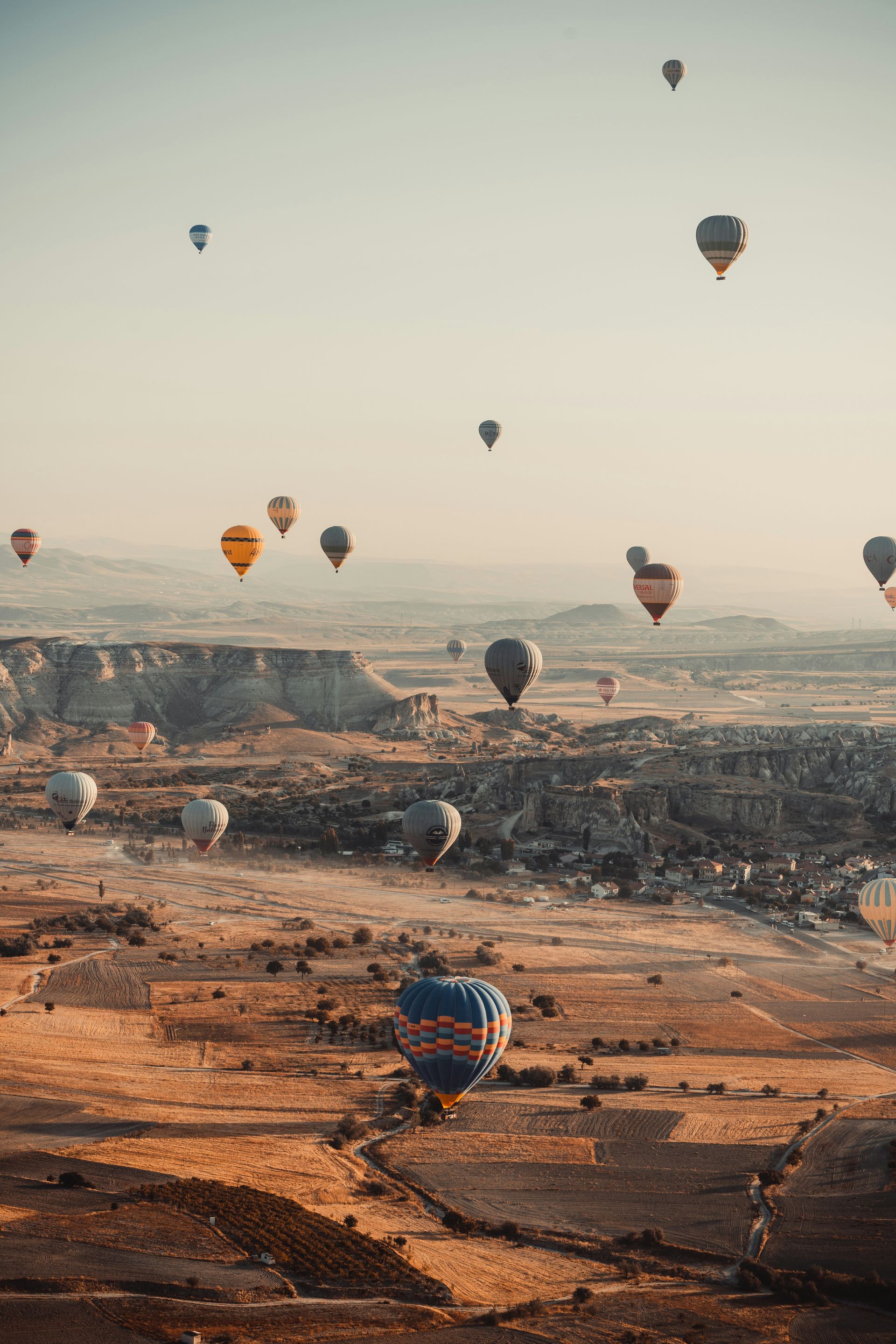 Hot air balloons soar over a desert landscape at sunrise in Cappadocia, Turkey.