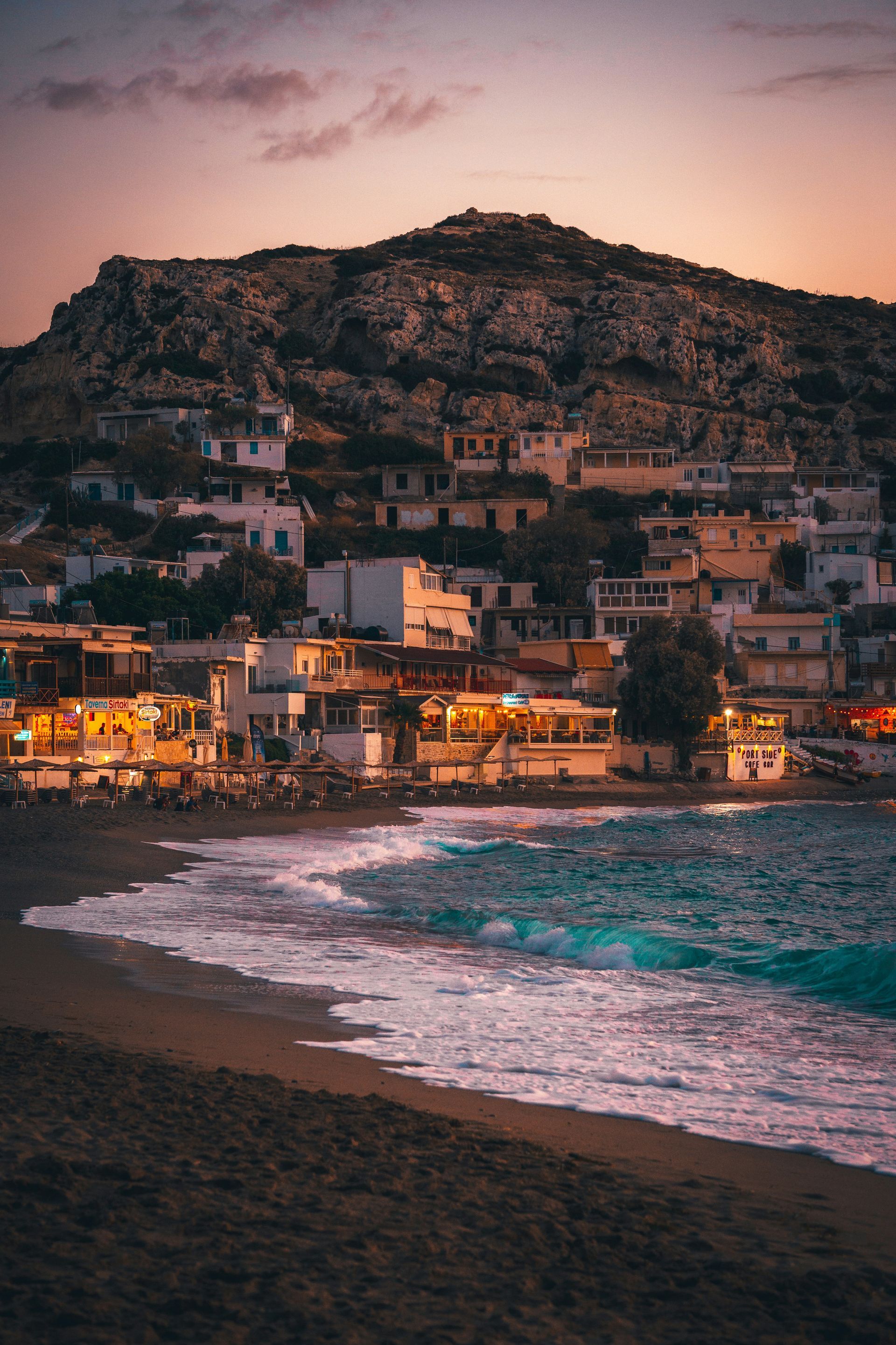 A beach with a mountain in the background at sunset in Crete, Greece.
