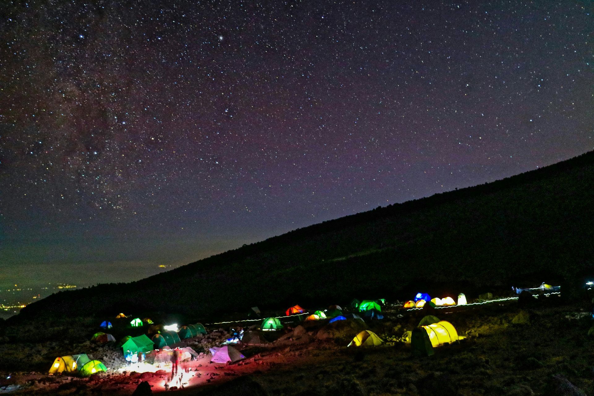 A group of tents are lit up under a starry night sky on Mount Kilimanjaro in Tanzania.