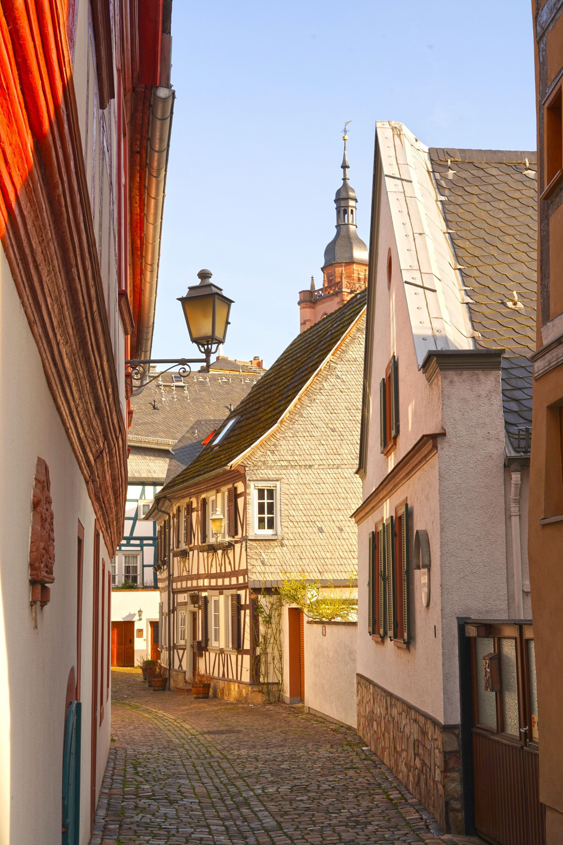 A narrow alleyway between two buildings with a church in the background in Eltville, Germany.
