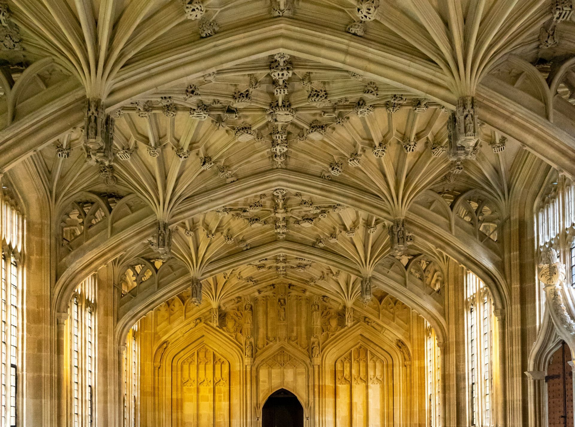 Ornate Gothic ceiling with detailed stone tracery and arched windows in Oxford, England.