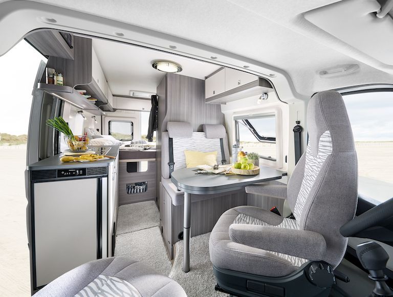 The inside of a camper van with a table and chairs in Iceland.