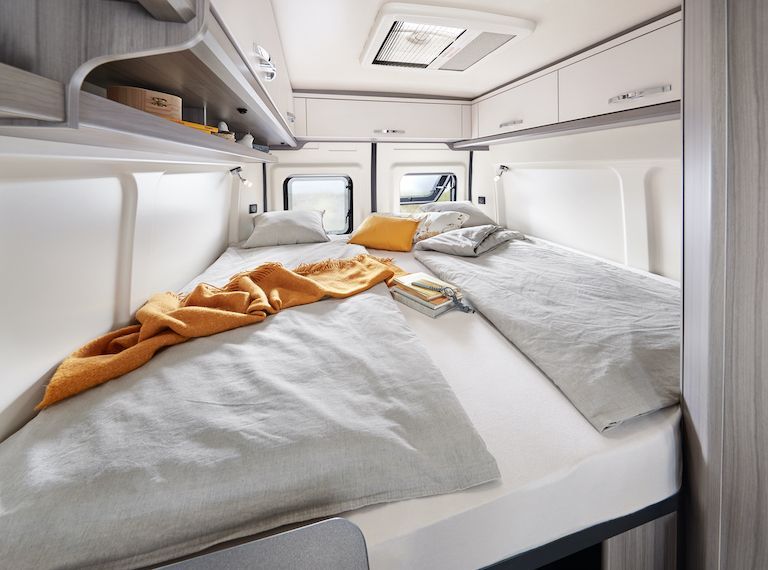 A bedroom in a van with two beds and a book on the bed in Iceland.