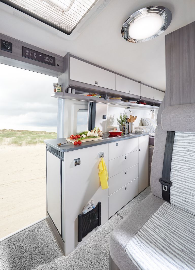 The inside of a camper van with a kitchen and a bed in Iceland.