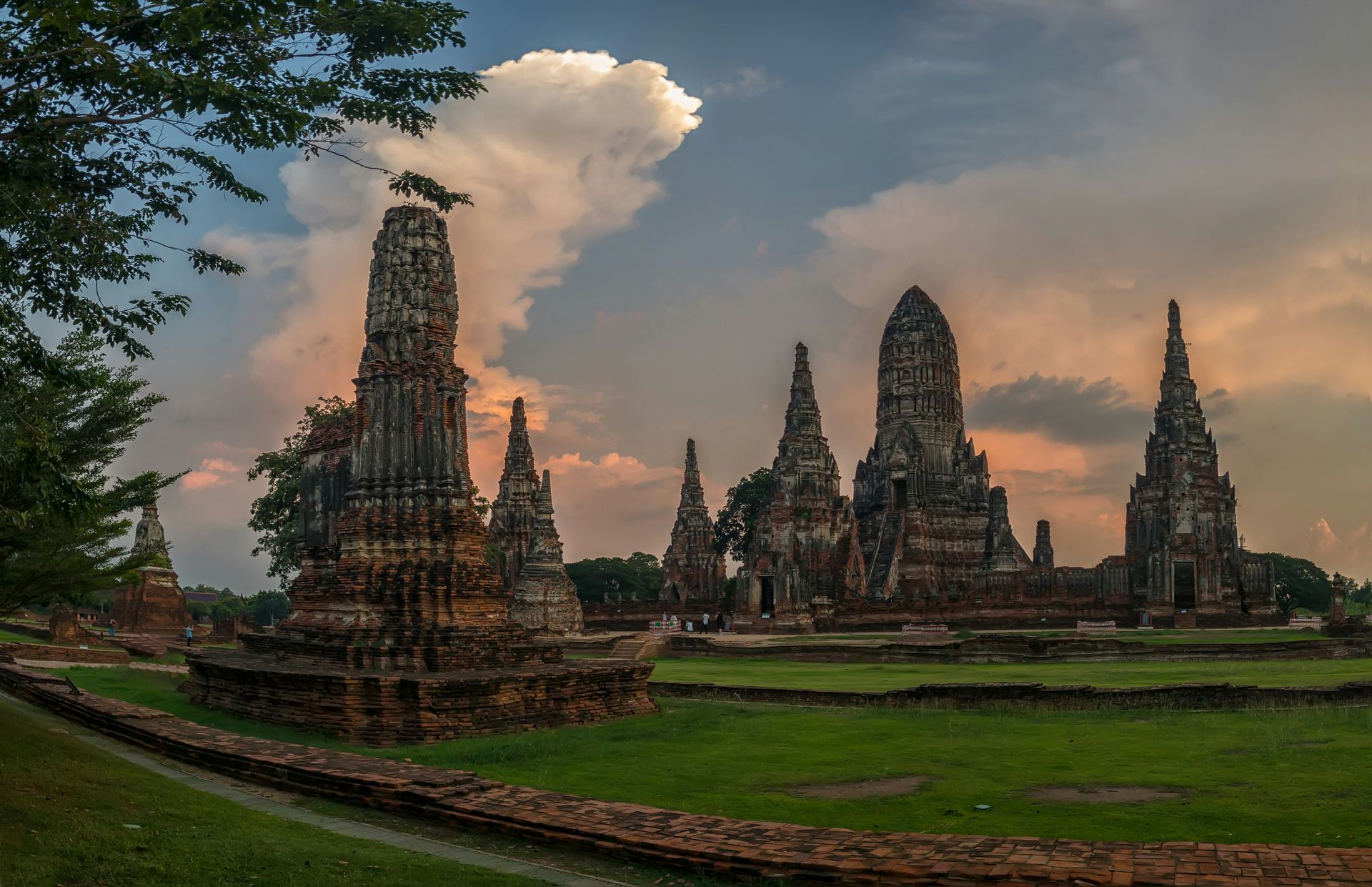 A row of ancient temples are surrounded by grass and trees in Ayutthaya, Thailand.