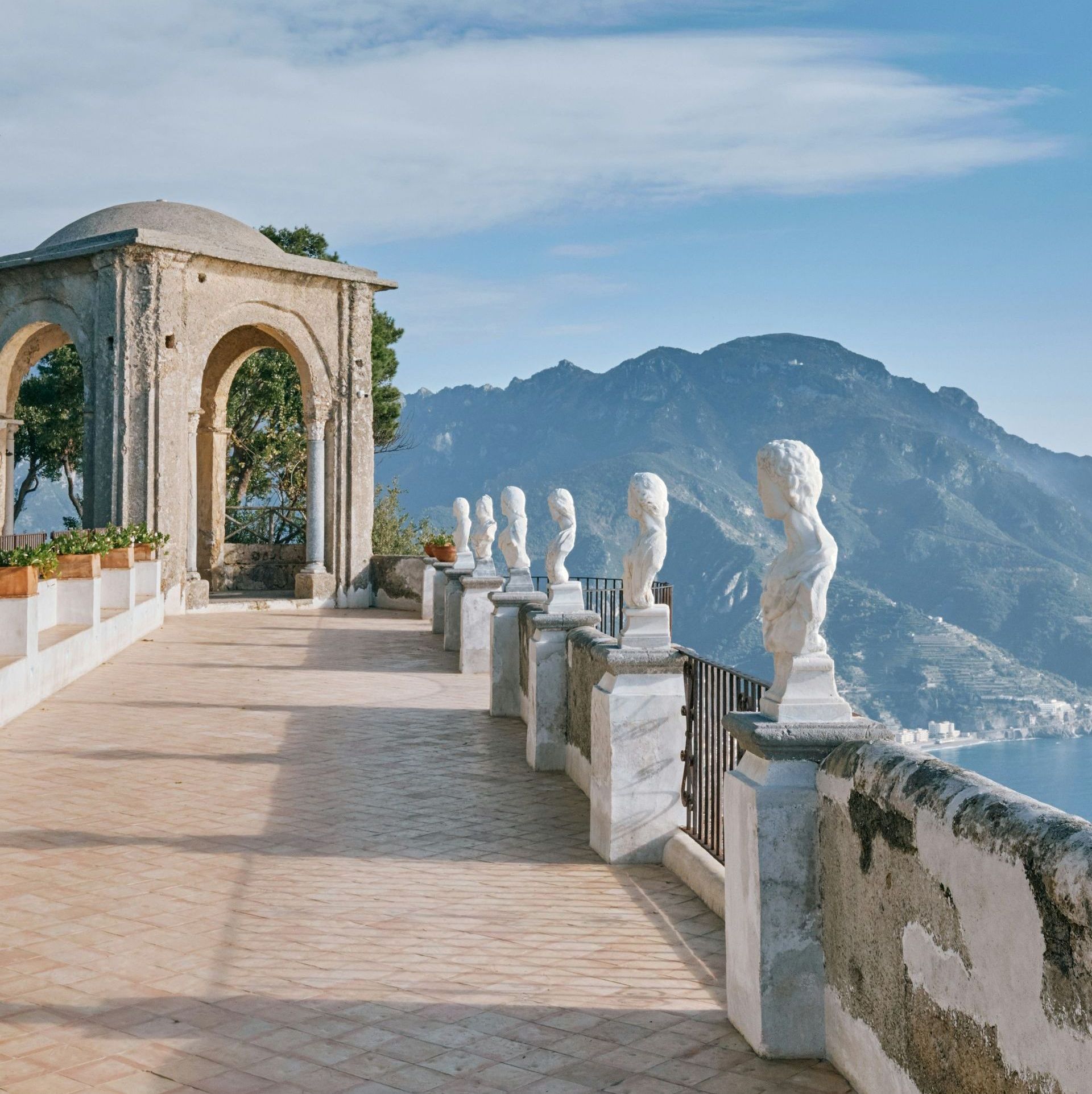 A row of statues on a balcony overlooking a mountain range on Lake Como, Italy.