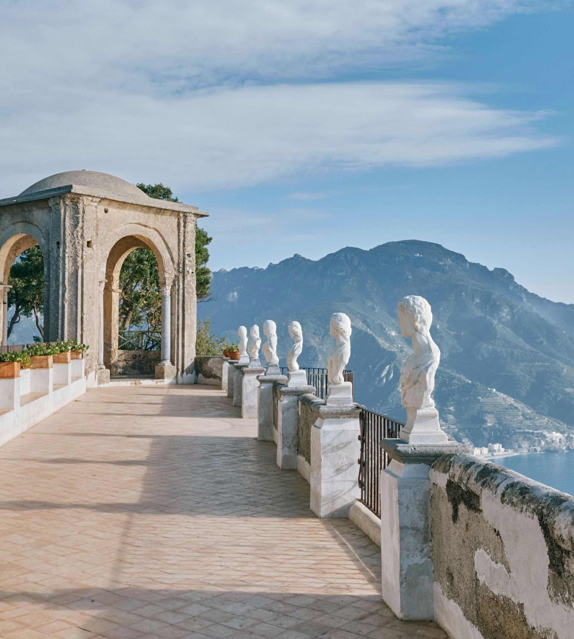 A row of statues on a balcony overlooking a mountain range on Lake Como, Italy.