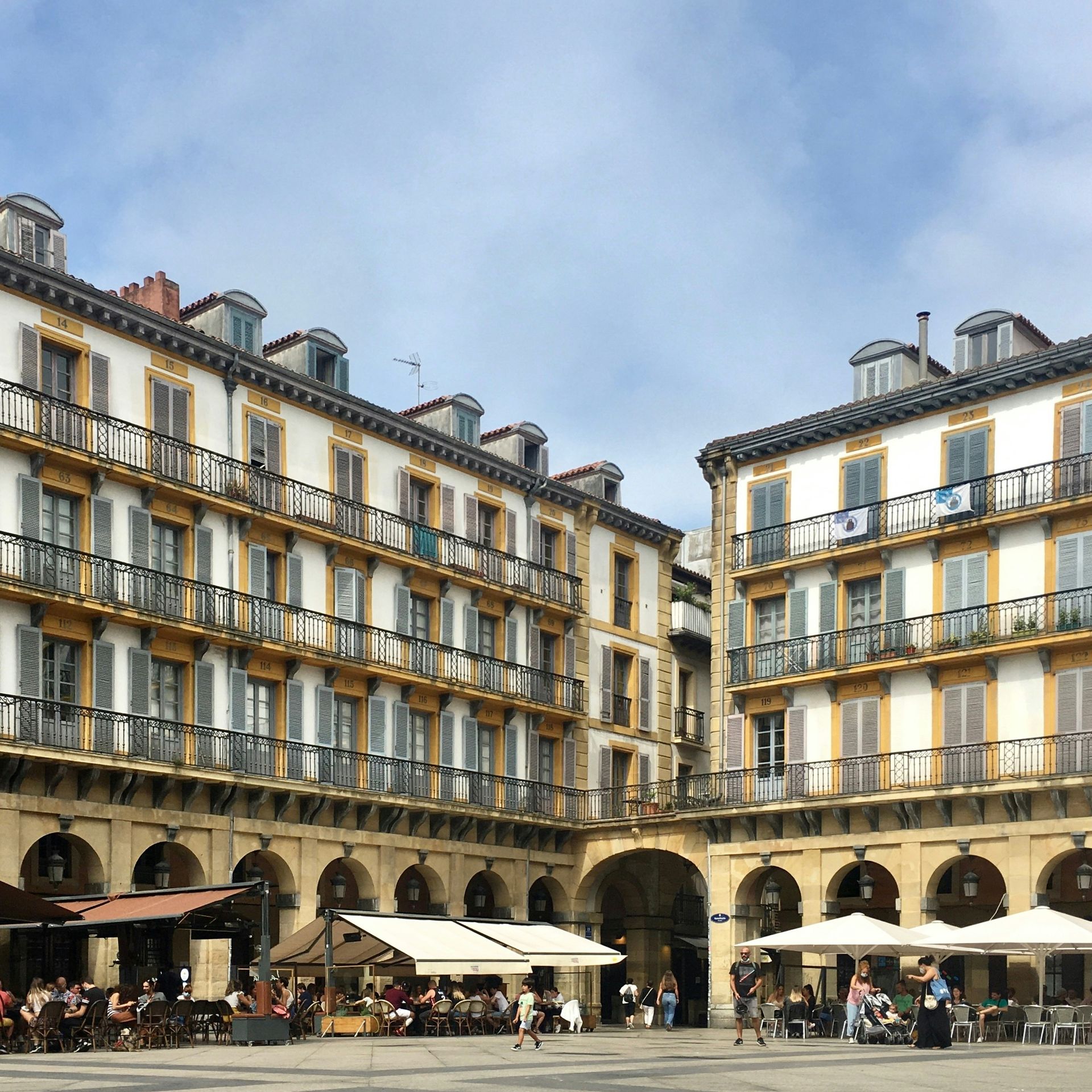 Plaza with ornate buildings surrounding a square with outdoor cafes in San Sebastián, Spain.
