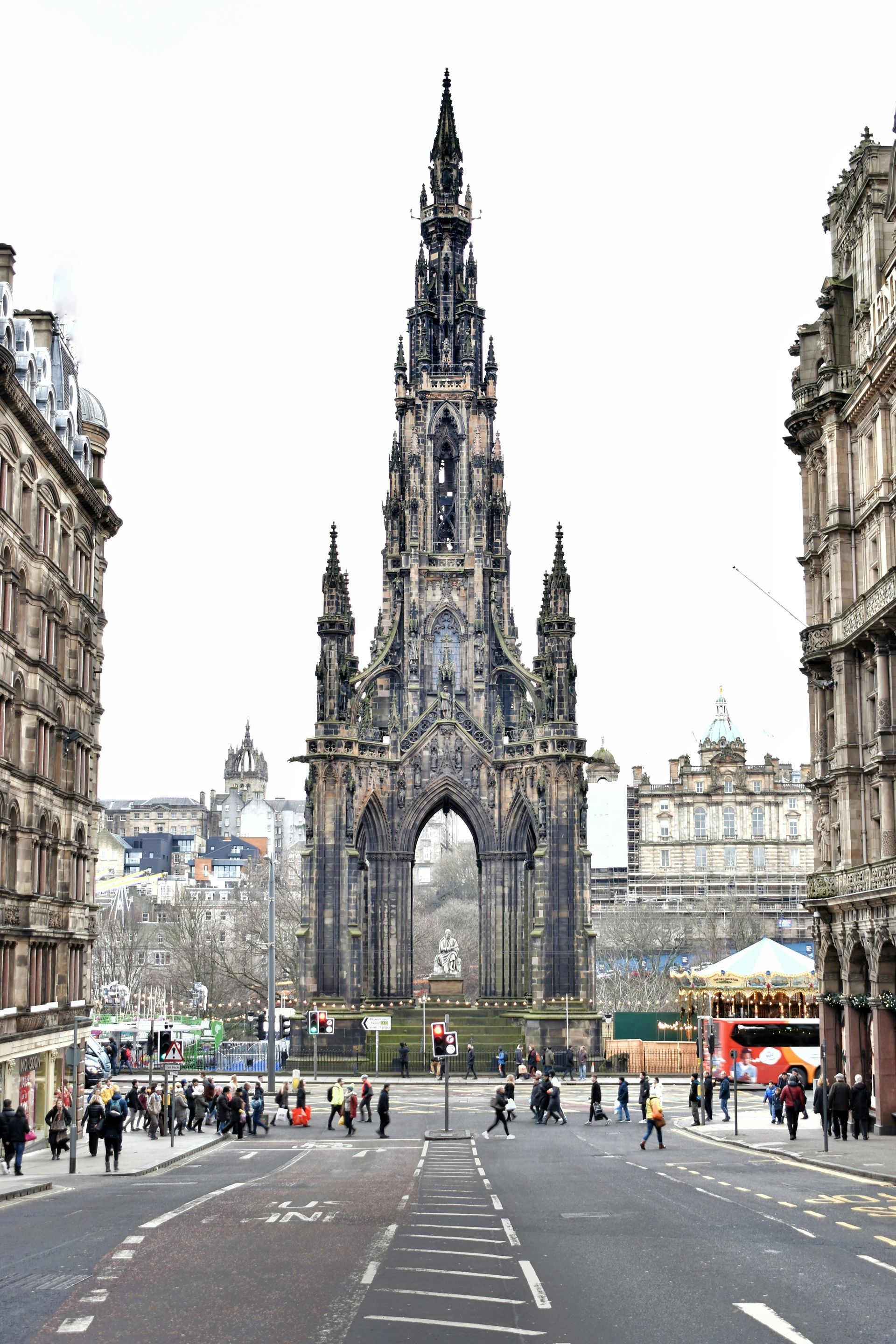 Scott Monument in Edinburgh, Scotland, framed by buildings on either side of a street. People are visible below.